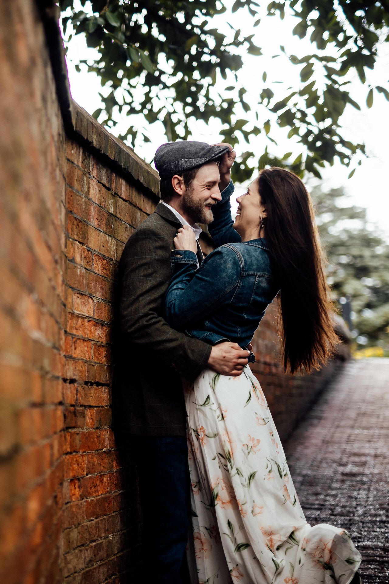 Couple sharing intimate moment against rustic brick wall backdrop.
