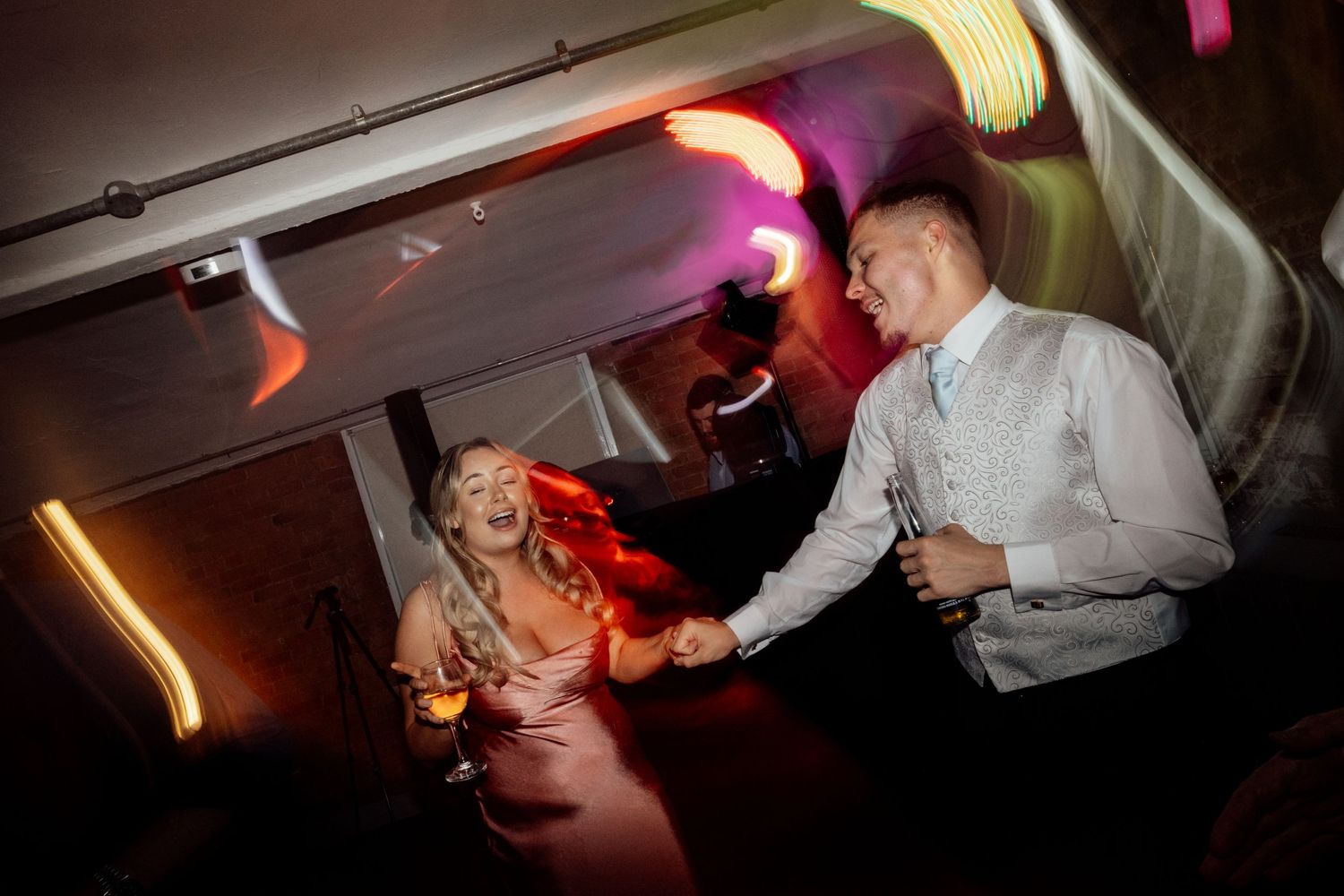 Wedding reception dance party with colorful lighting and dancing guests.