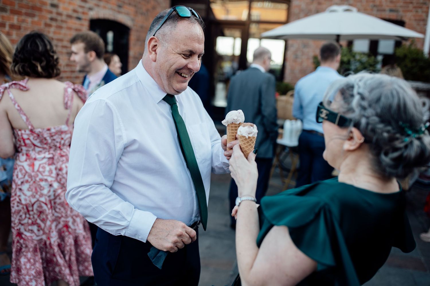 Wedding guests socializing outside a rustic brick venue during cocktail hour.