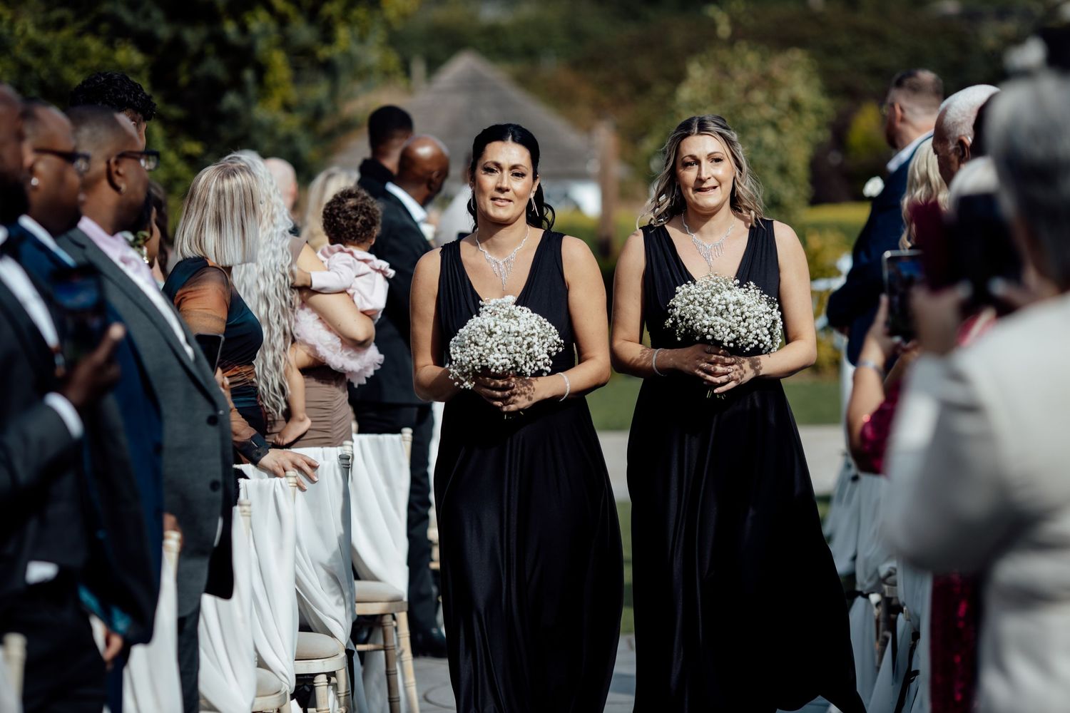 Wedding party members in formal black attire pose during celebration.