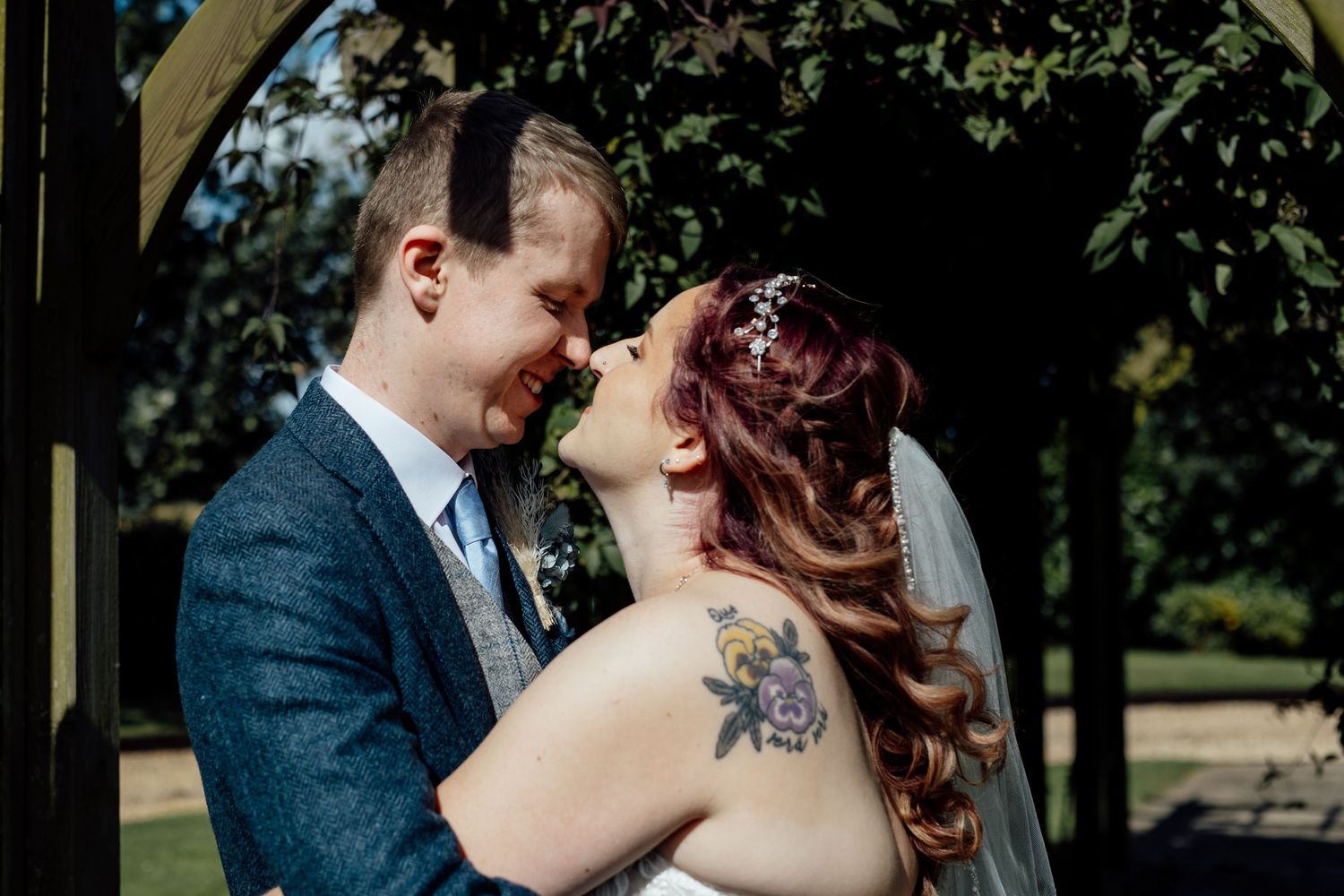 Joyful moment shared under a garden arch with natural lighting.