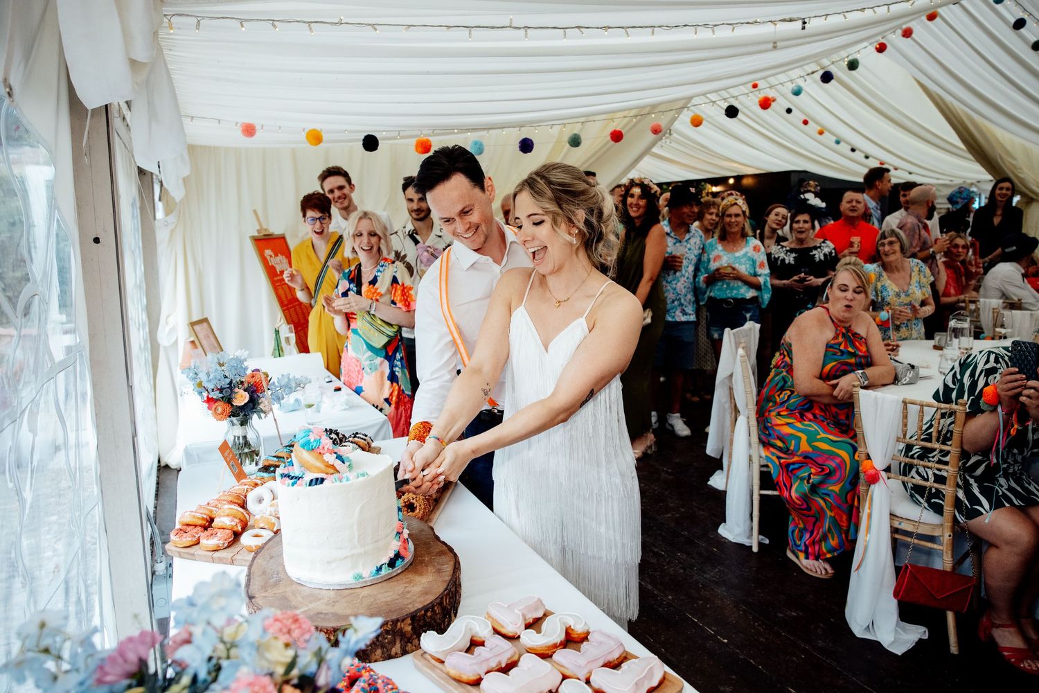 White tent decorated with bunting and string lights for a wedding celebration.