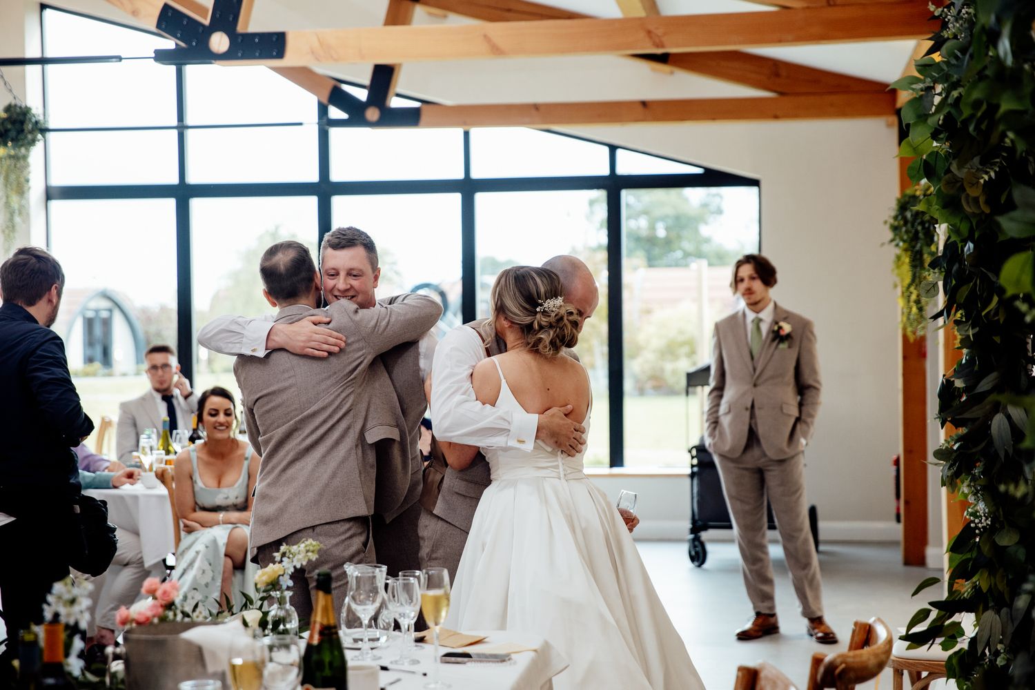Wedding reception in modern venue with exposed wooden beams and large windows.