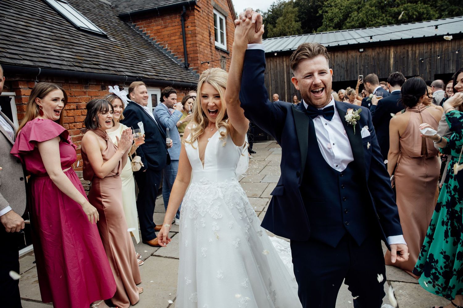 Wedding celebration with guests dancing and mingling outside brick buildings.