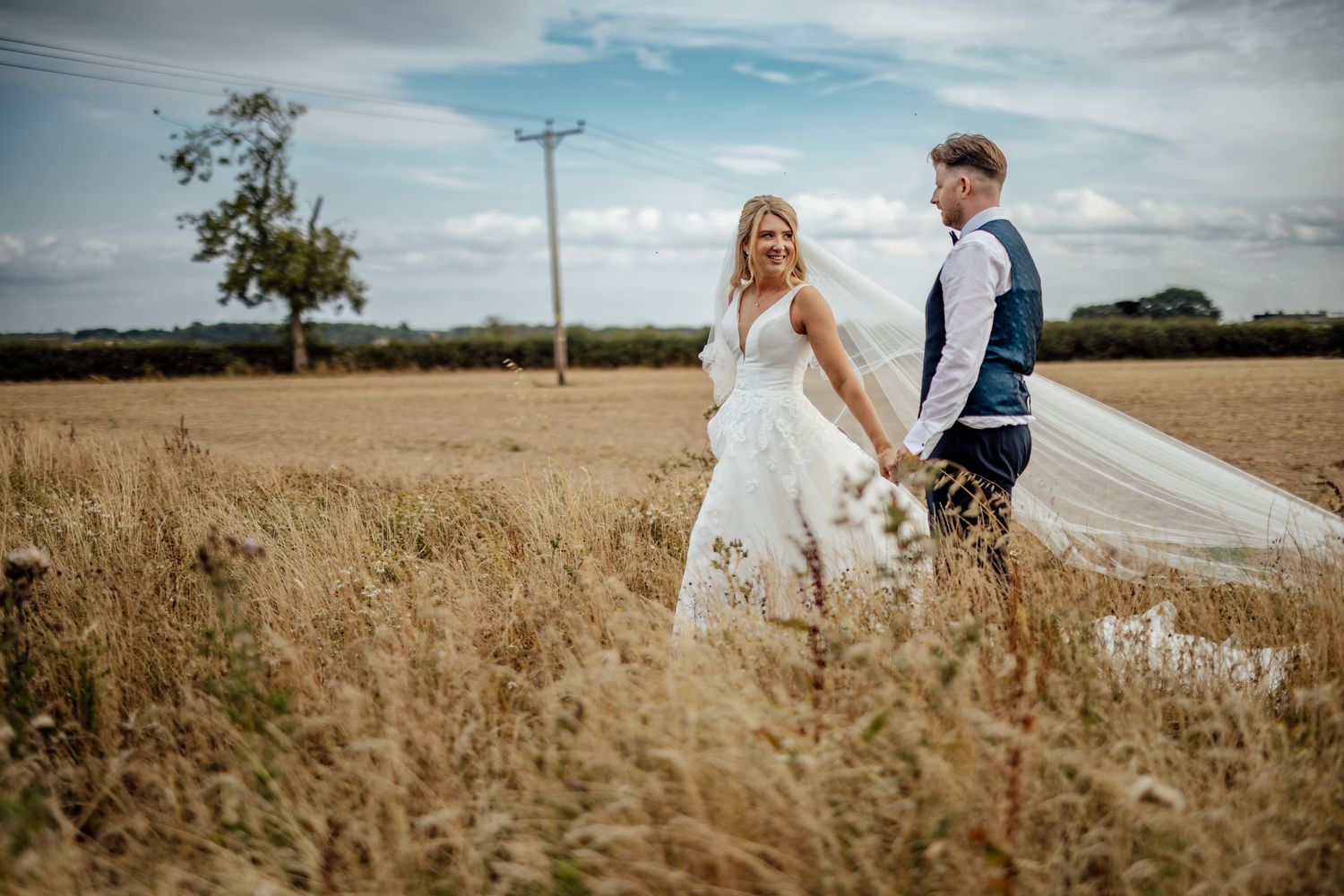 Wedding photography session in a rustic field with dramatic sky backdrop.