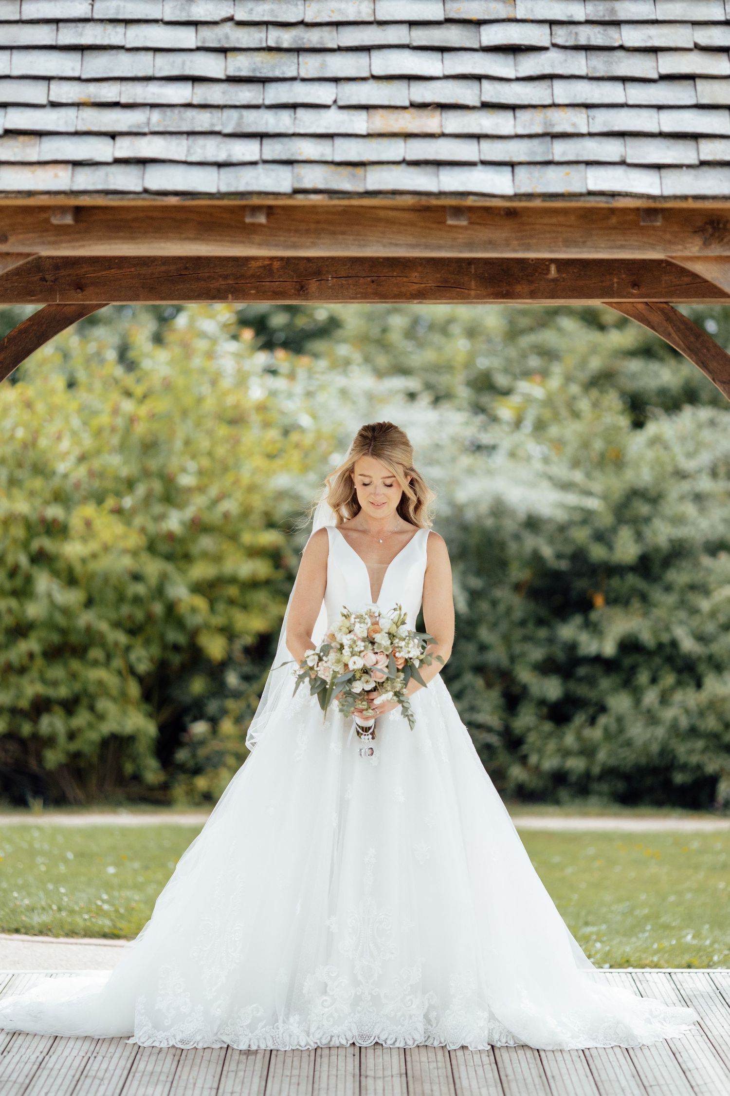 Elegant white wedding dress photographed against rustic wooden shingle background.
