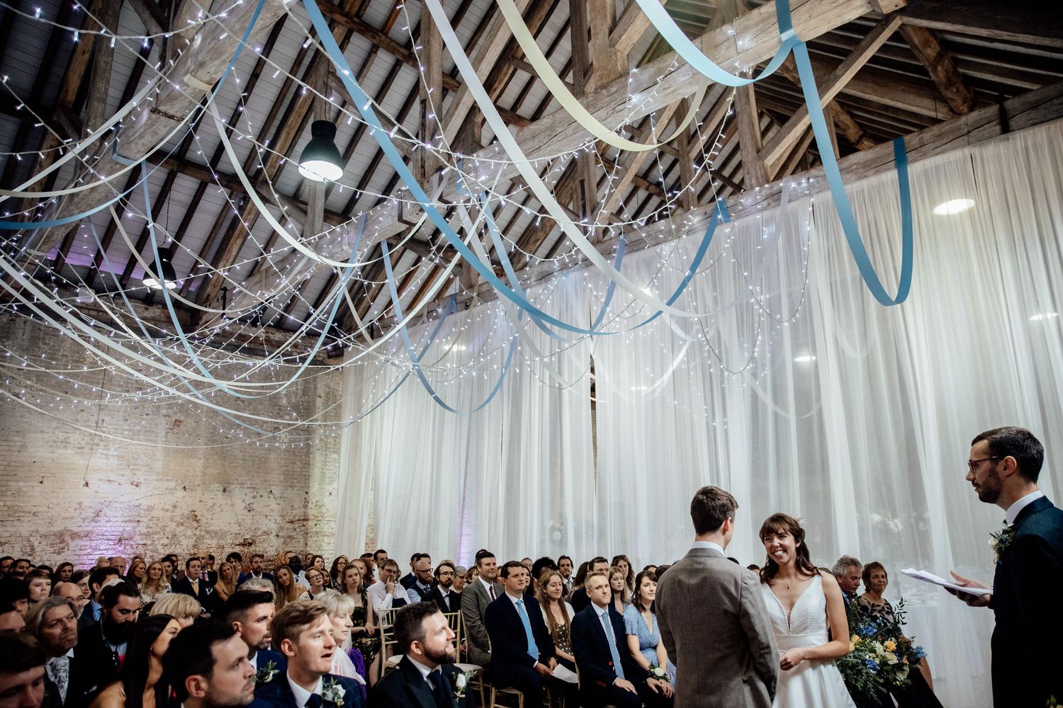 White draped ceiling with string lights creates an elegant reception atmosphere.