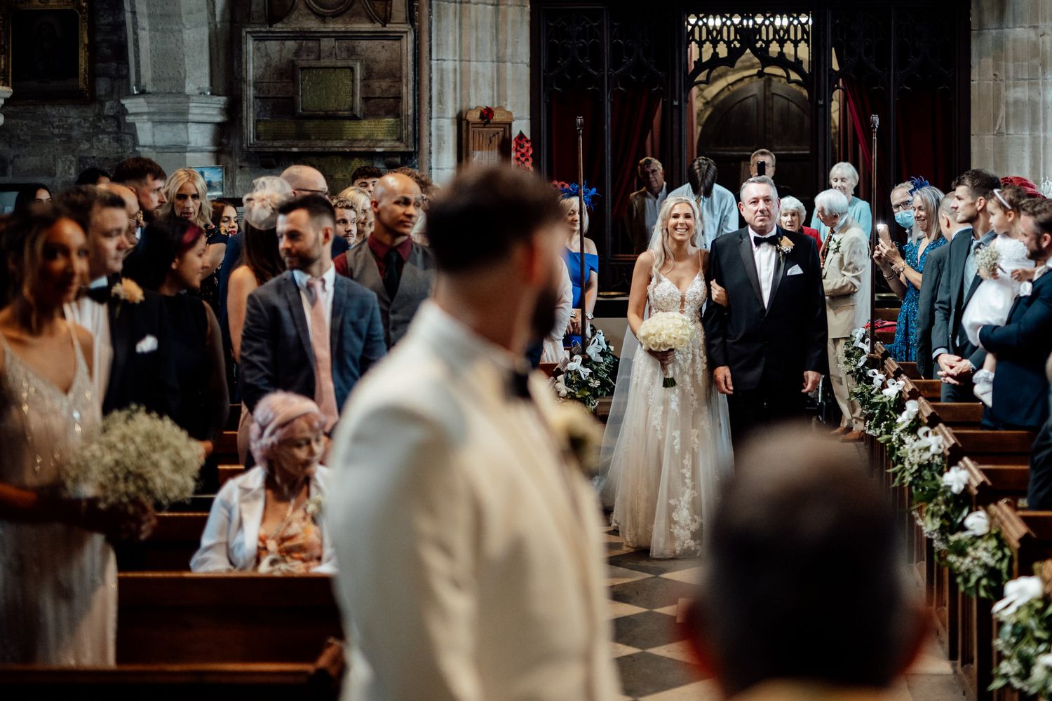 Traditional church ceremony with floral arrangements decorating the aisle.