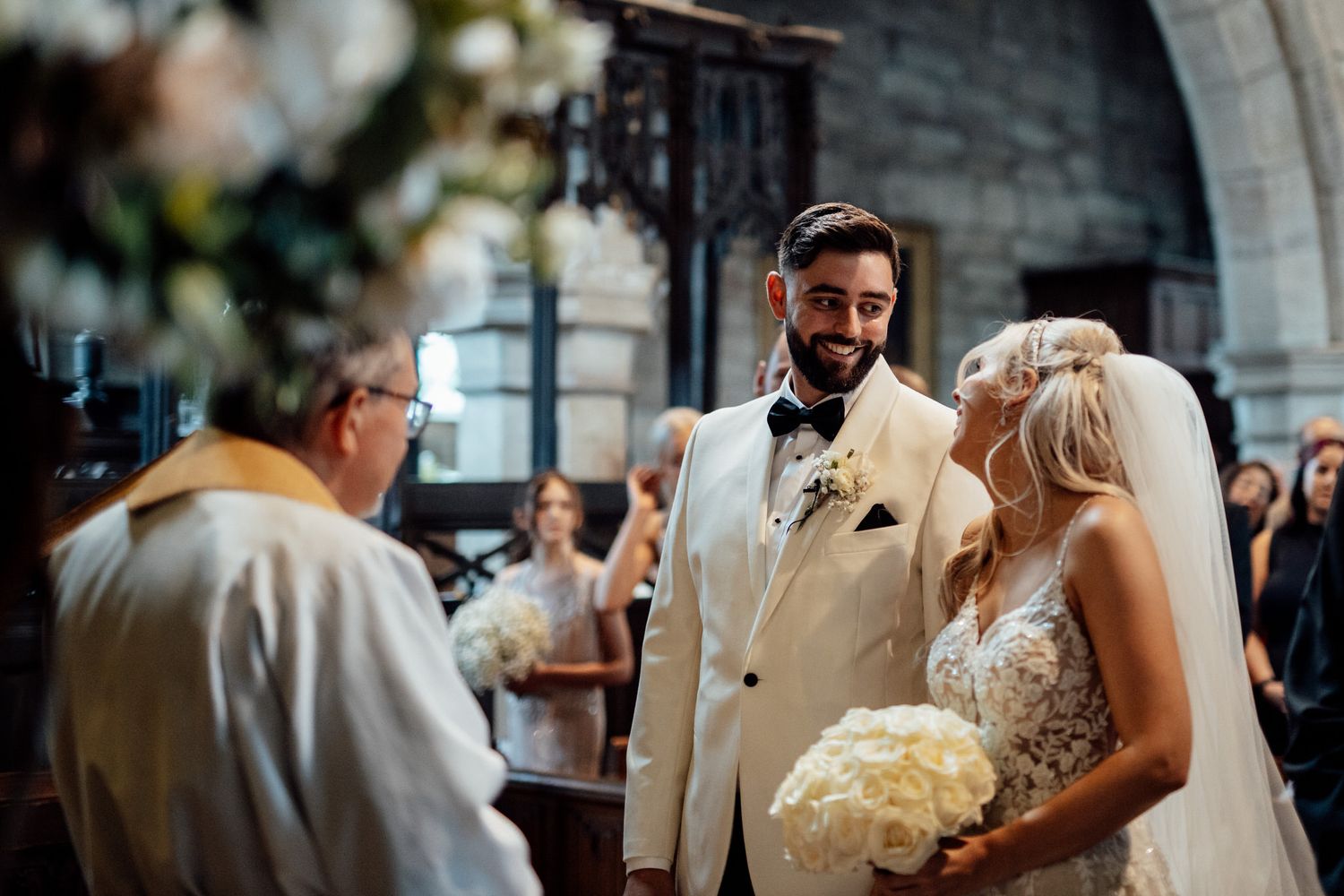 Wedding ceremony in historic stone church with elegant floral arrangements.