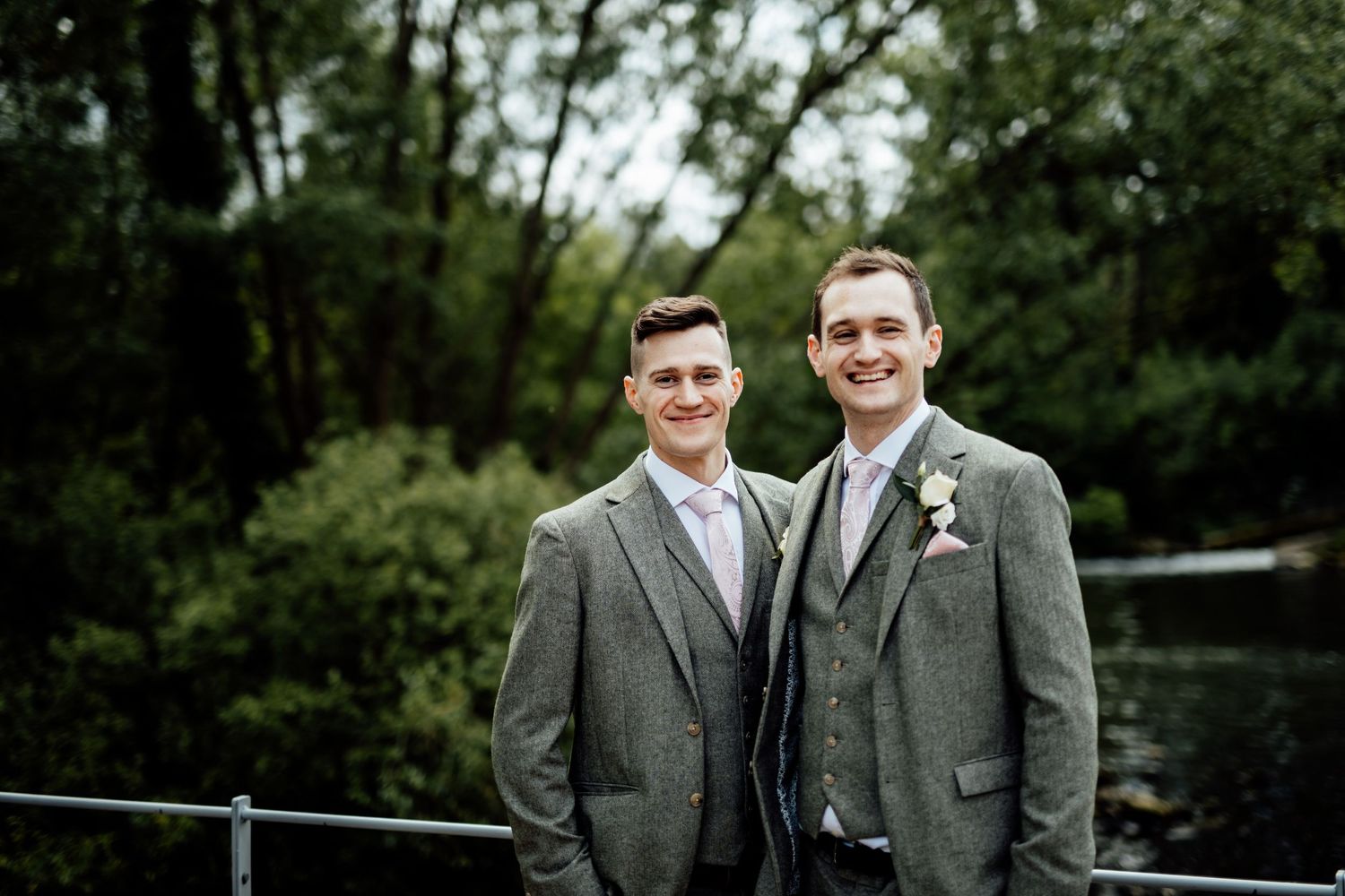 Groomsmen in grey suits posing outdoors on a cloudy day.