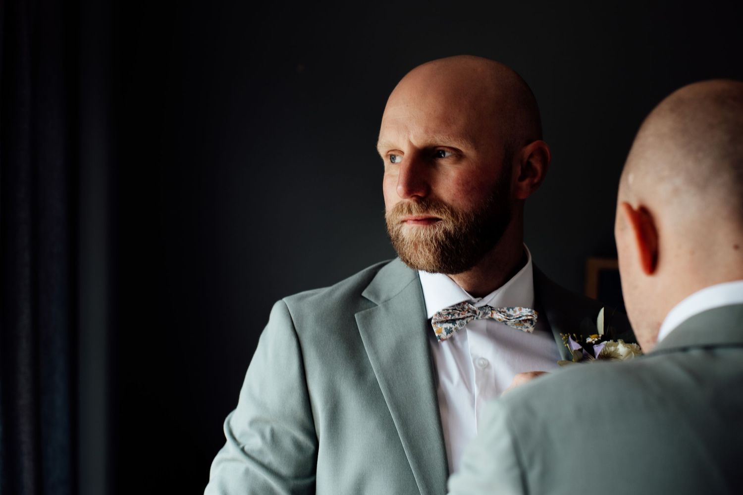 Formal wedding attire preparation in a dimly lit room with elegant details.