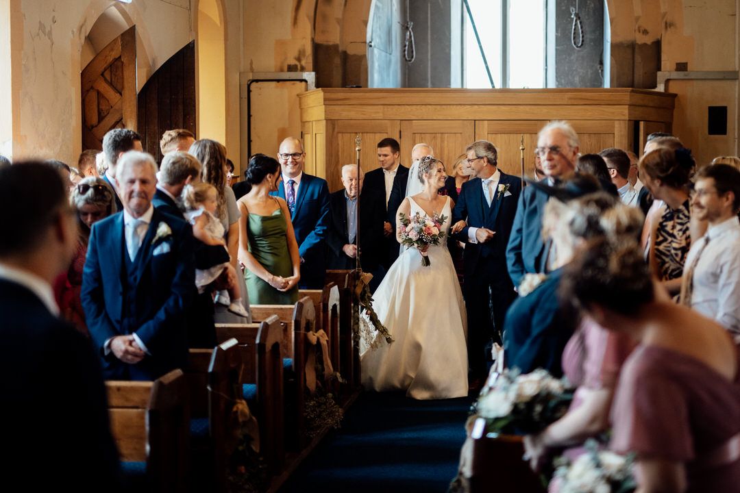 Wedding ceremony in a beautiful church with stained glass windows and stone archways.