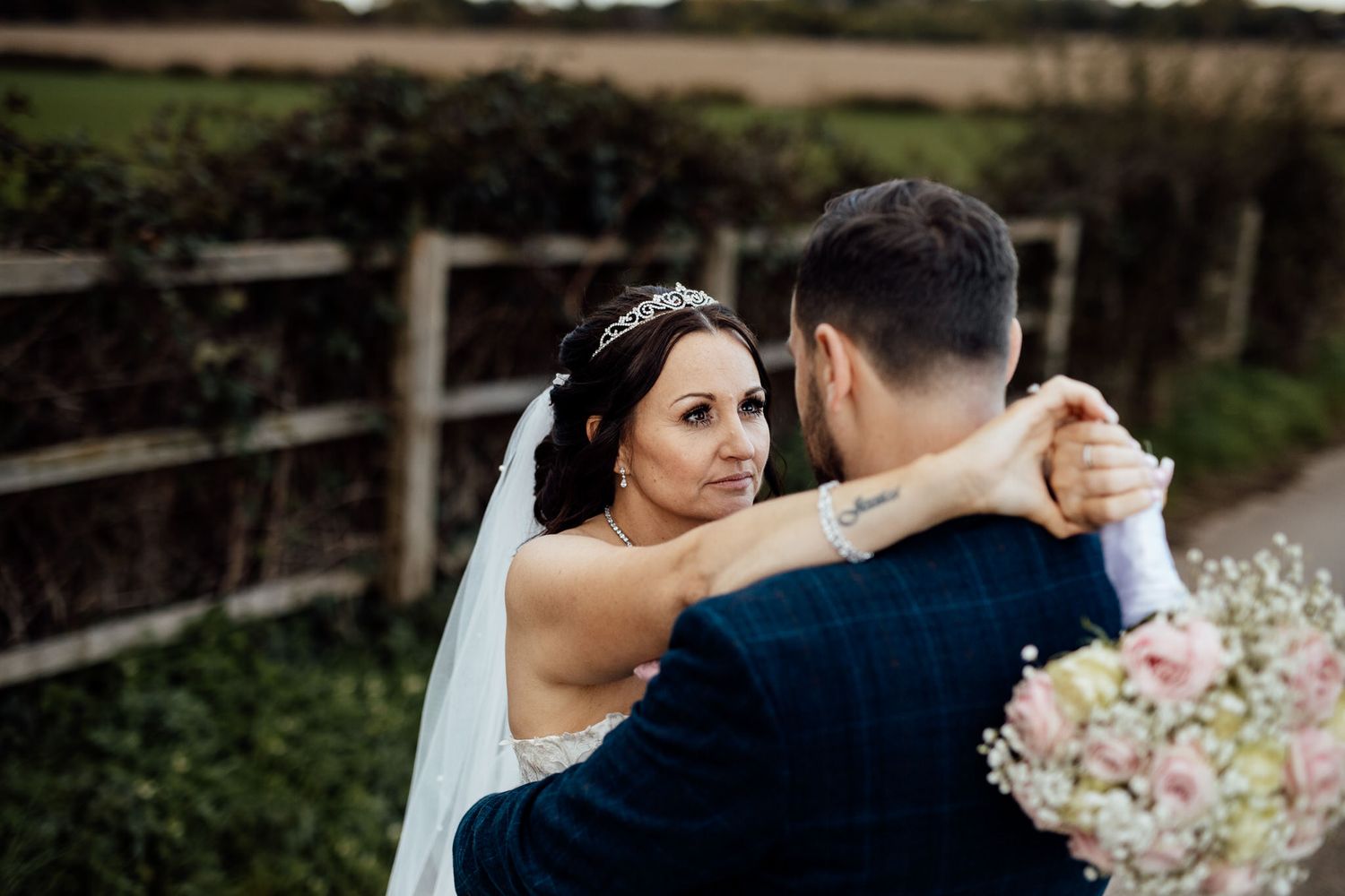 Romantic wedding couple embracing in an outdoor garden setting.