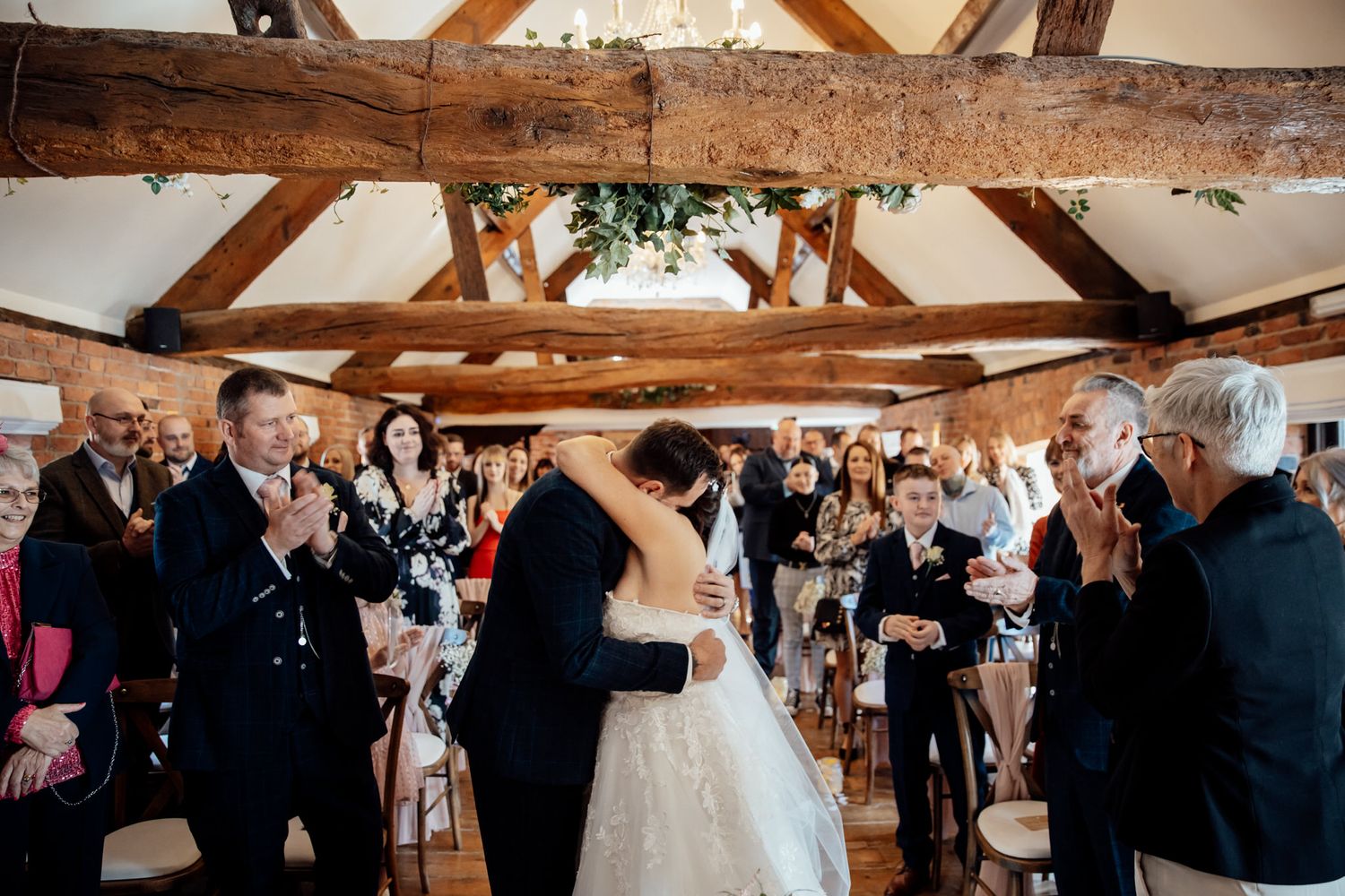 Wedding reception celebration in rustic barn venue with exposed wooden beams.
