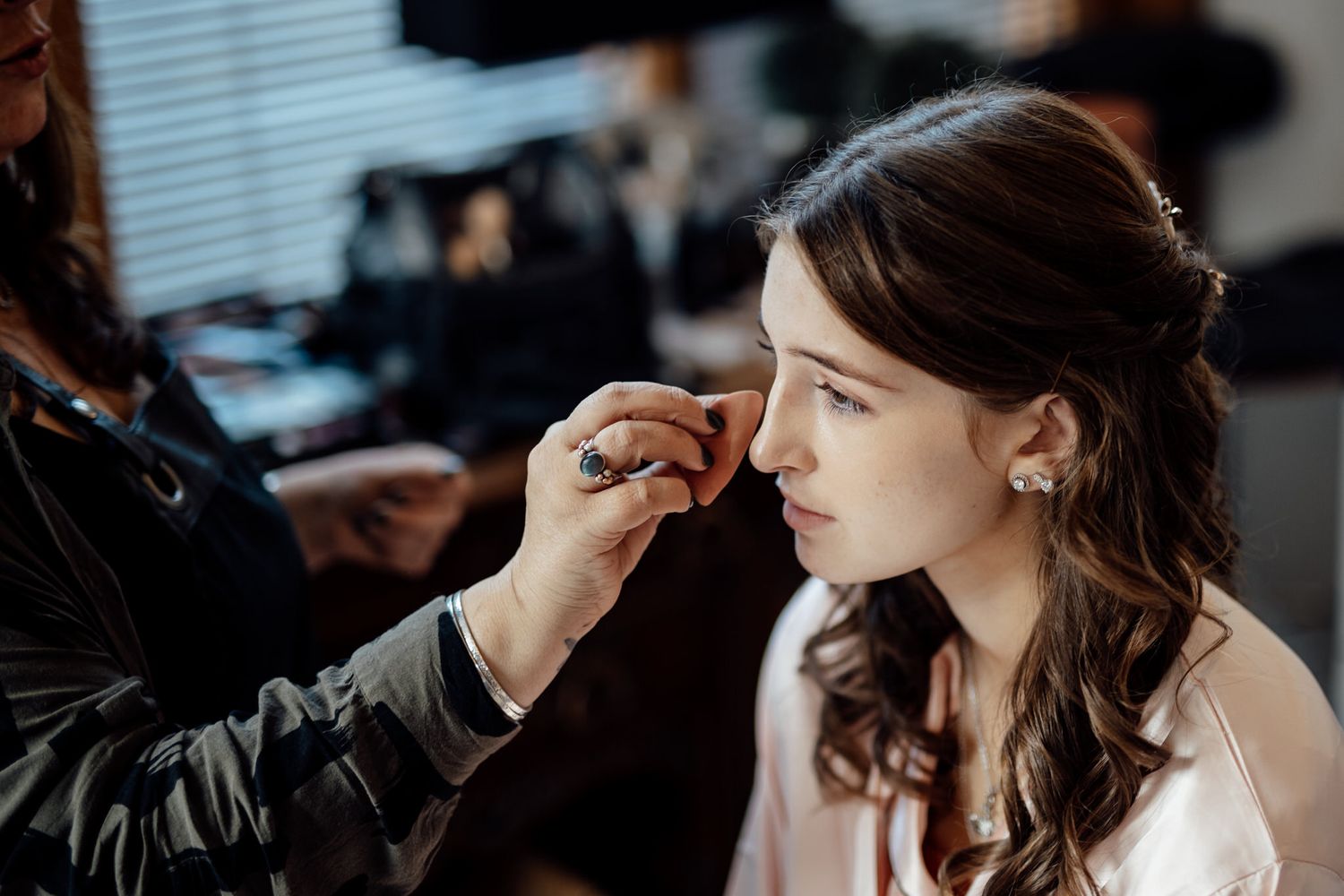 Professional makeup artist applies finishing touches during bridal preparation.