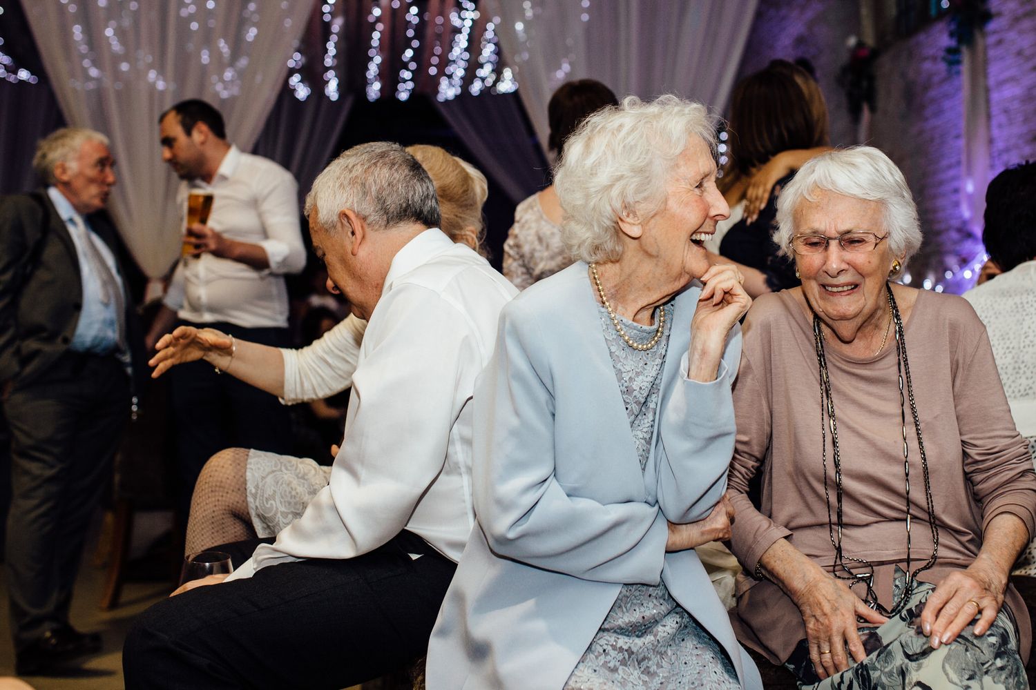 Elderly guests sharing laughs during a wedding reception.
