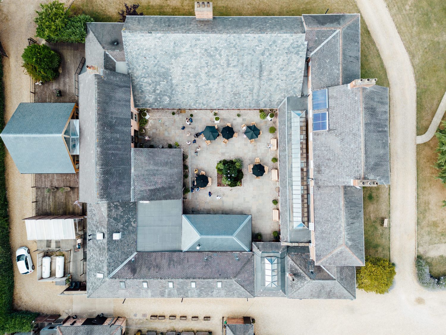 Aerial view of a courtyard building with grey roof and outdoor seating area.