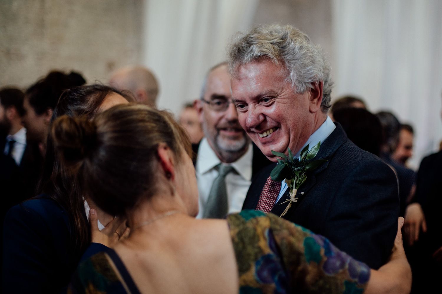 Wedding guests share joyful moments during an indoor reception celebration.