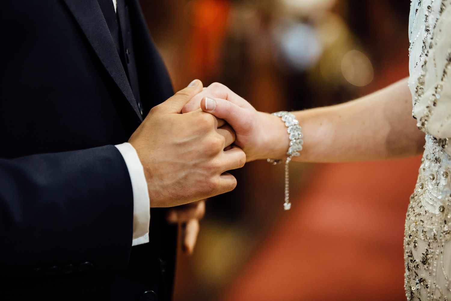 Close-up of hands exchanging rings during wedding ceremony.