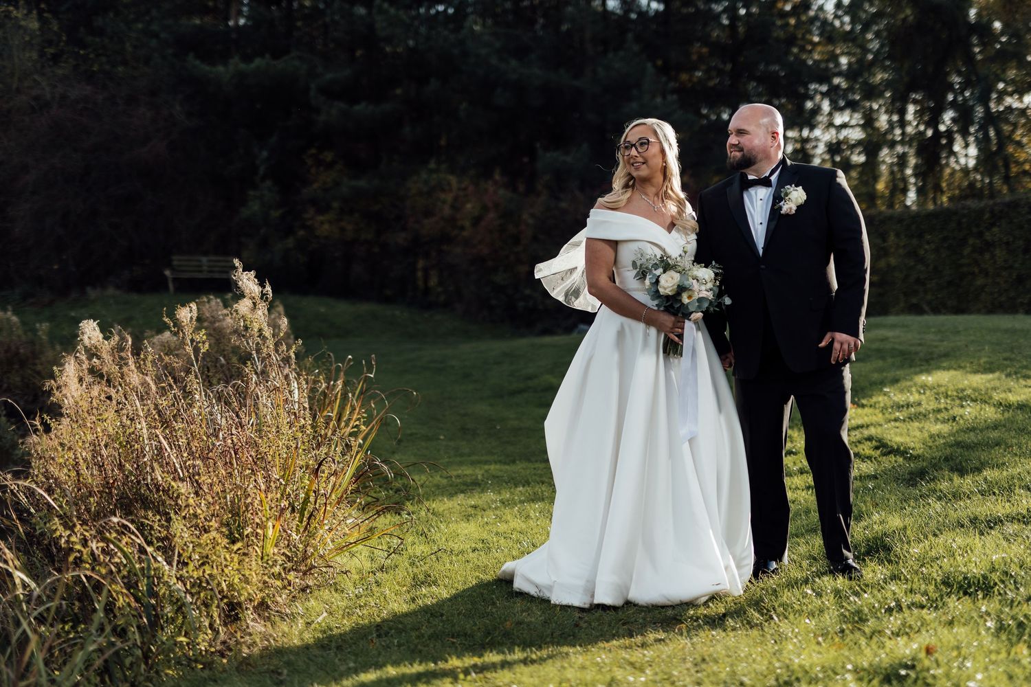 Romantic outdoor wedding portraits by a serene lake during golden hour.
