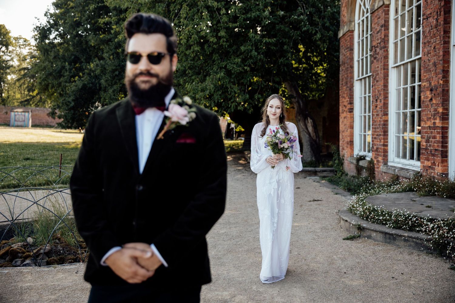 Wedding party portraits outside historic brick building on sunny day.