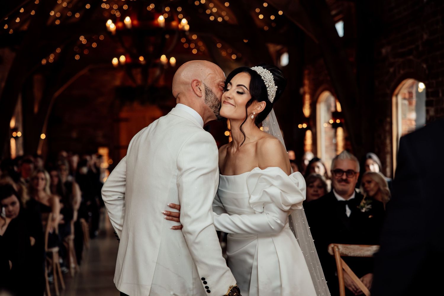 Romantic wedding moment in an elegant venue with exposed brick and ambient lighting.