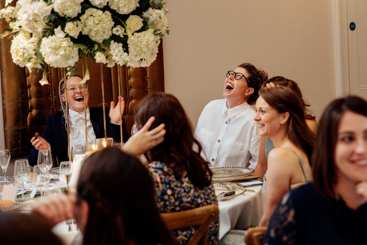 Wedding reception dinner with white floral centerpieces and guests enjoying the celebration.