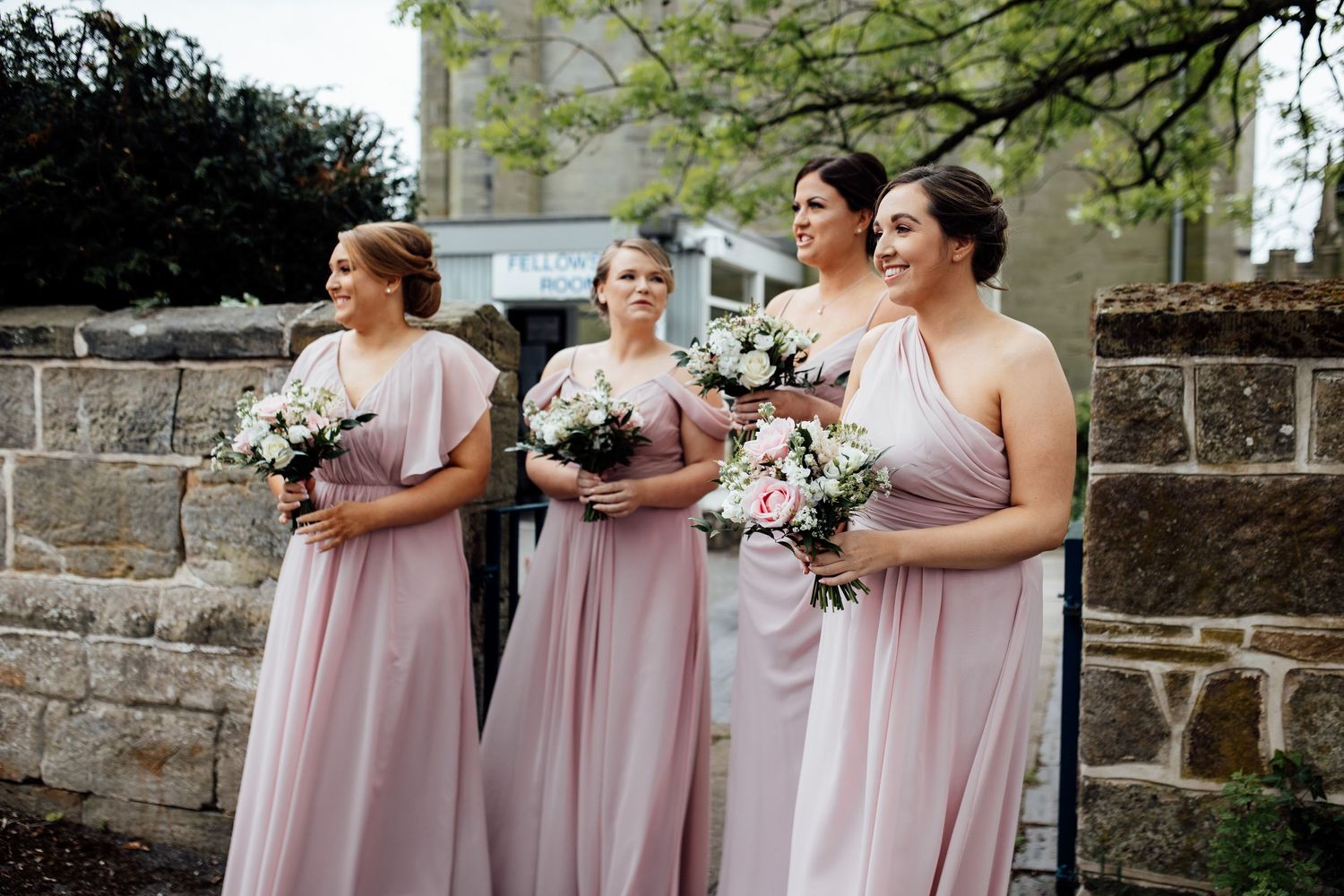 Bridesmaids in pink dresses walking together outdoors at a wedding venue.