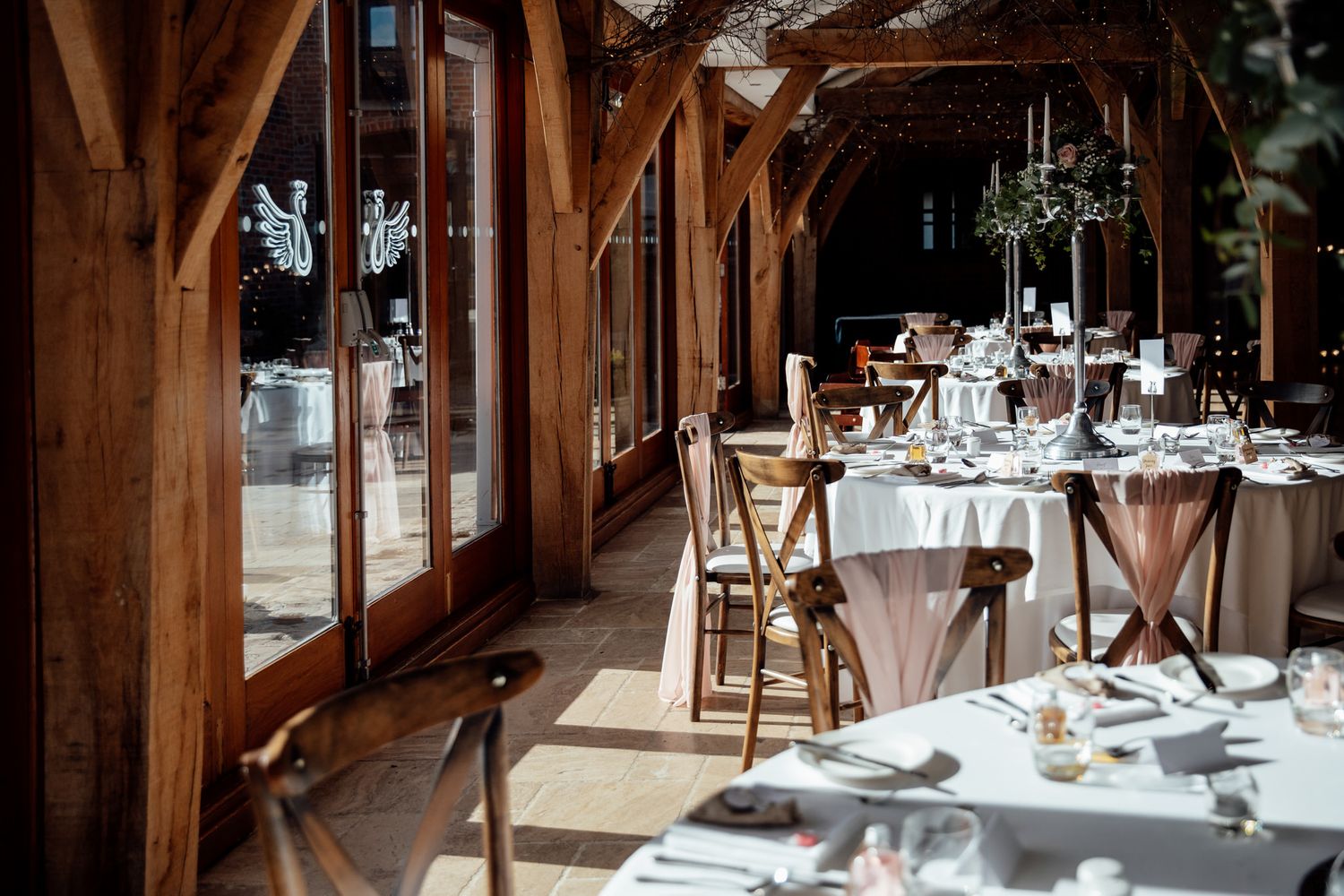 Elegant table settings in rustic wooden barn venue with natural lighting.