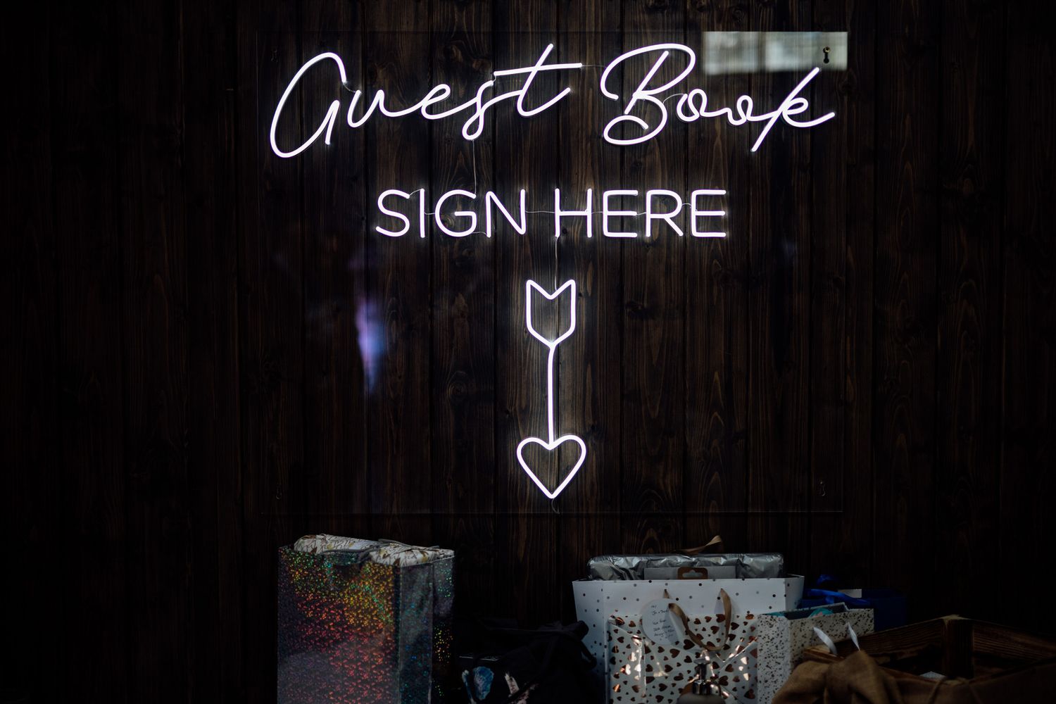 Illuminated neon wedding signs glowing against dark background.