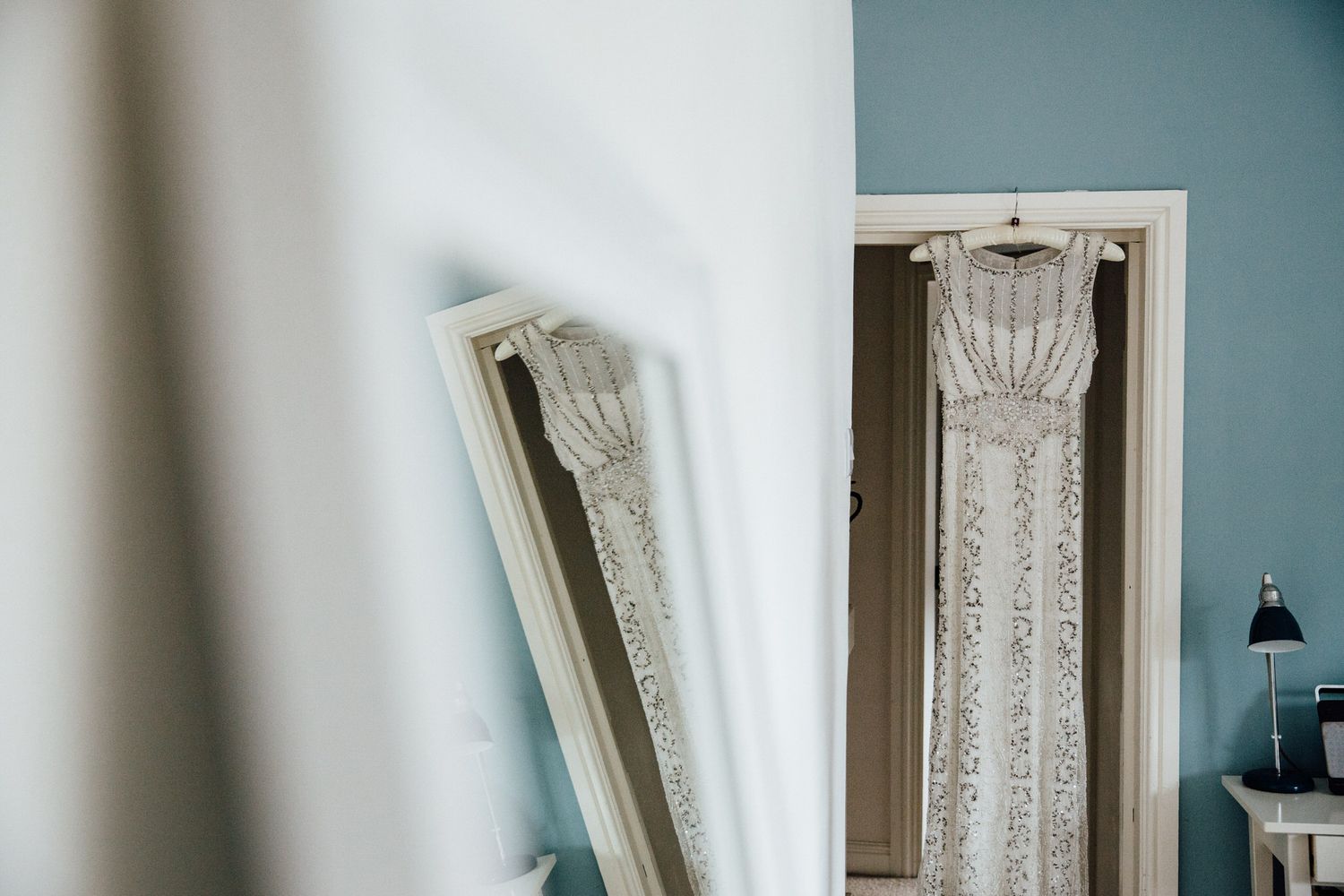 Soft natural light streaming through white lace curtains in a blue-walled room.