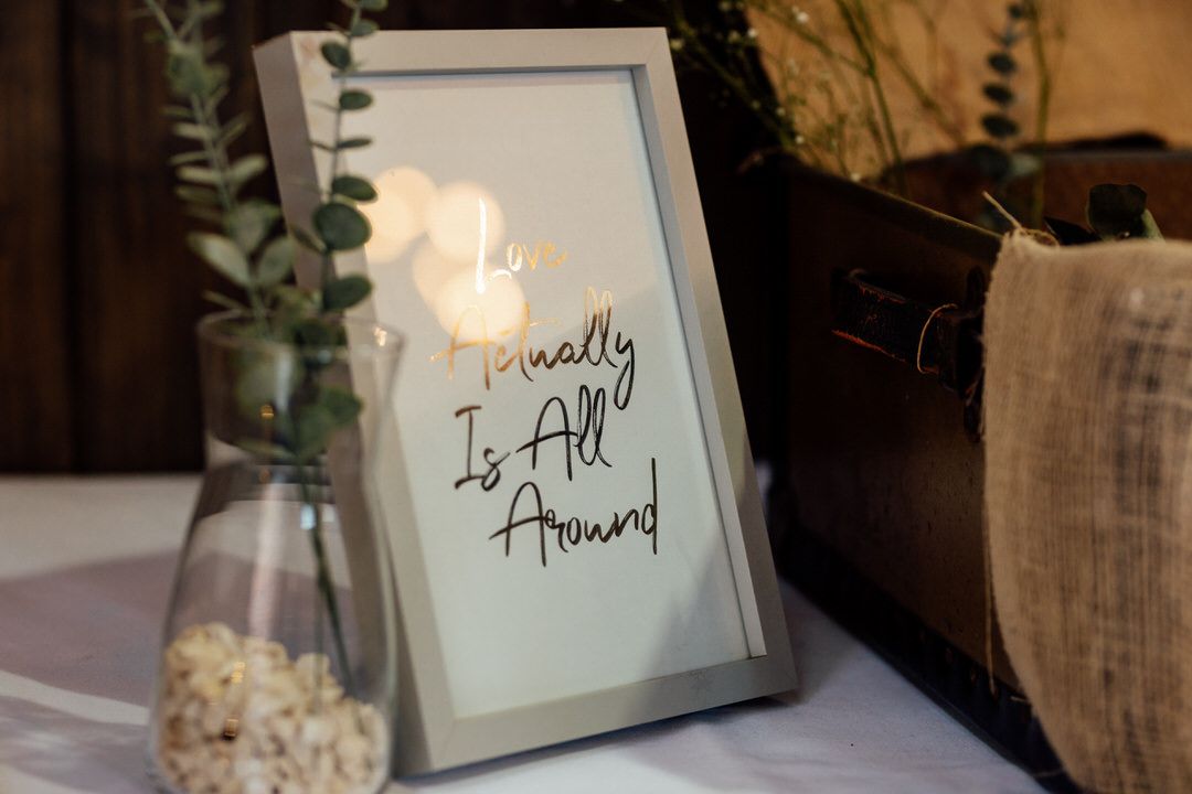 Wedding reception signage in elegant frames with greenery accents.