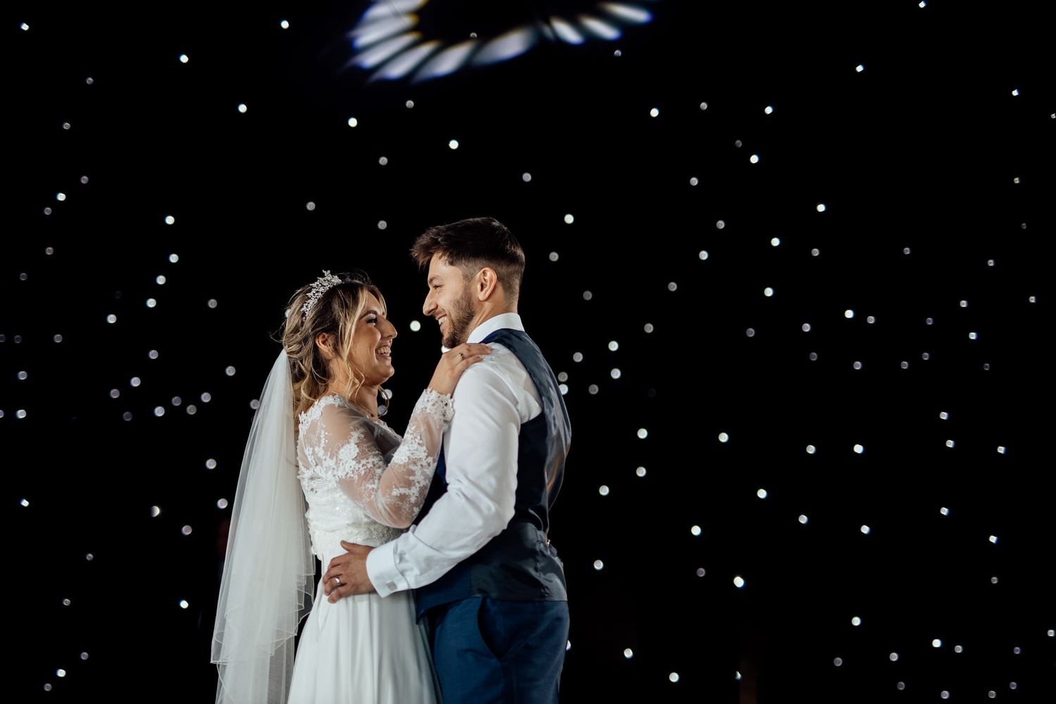 Romantic wedding couple shares intimate moments under a starry night sky at their reception.