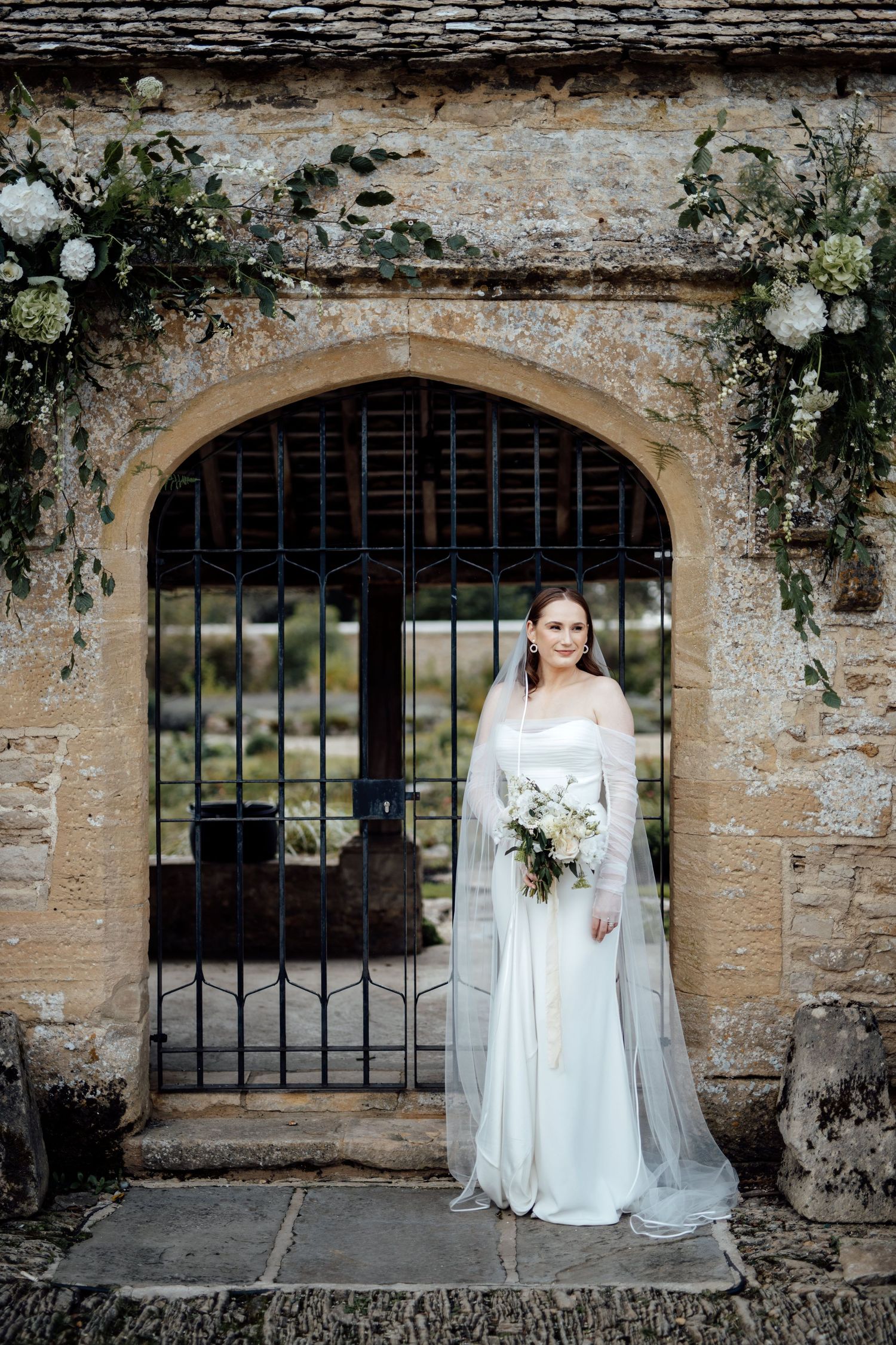 Bridal portraits taken against stone archways with climbing vines and iron gates.