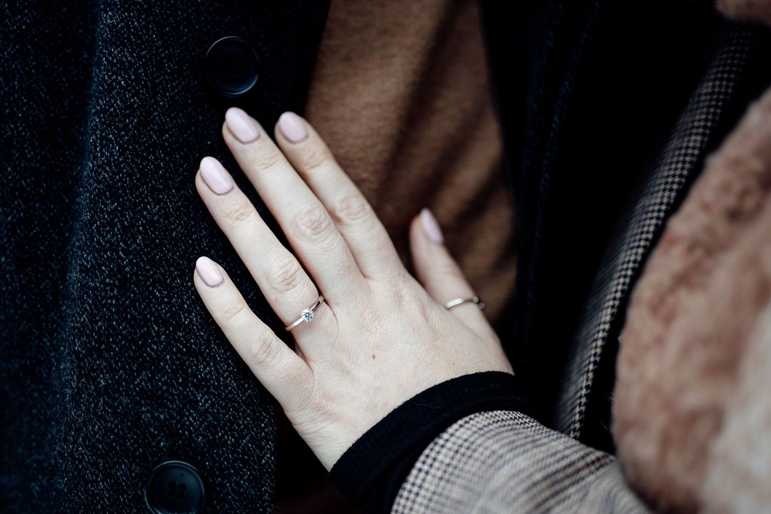 Close-up shot of hands displaying engagement rings during a winter photo session.