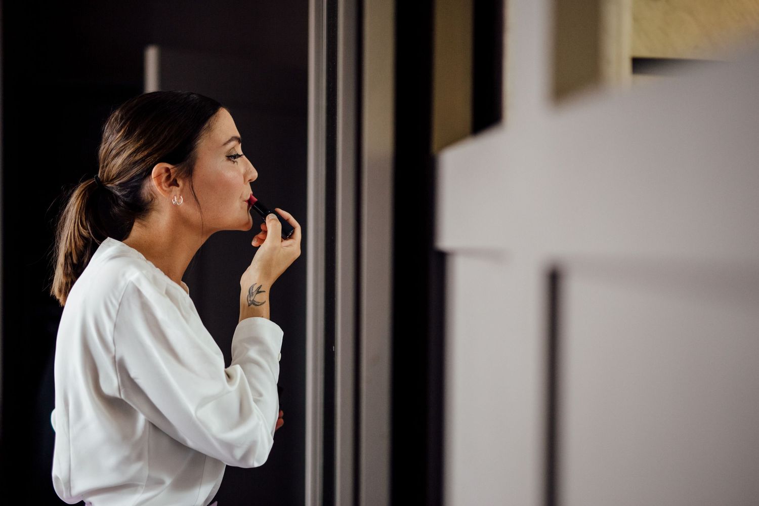 Person in white shirt stands in profile against dark interior background.