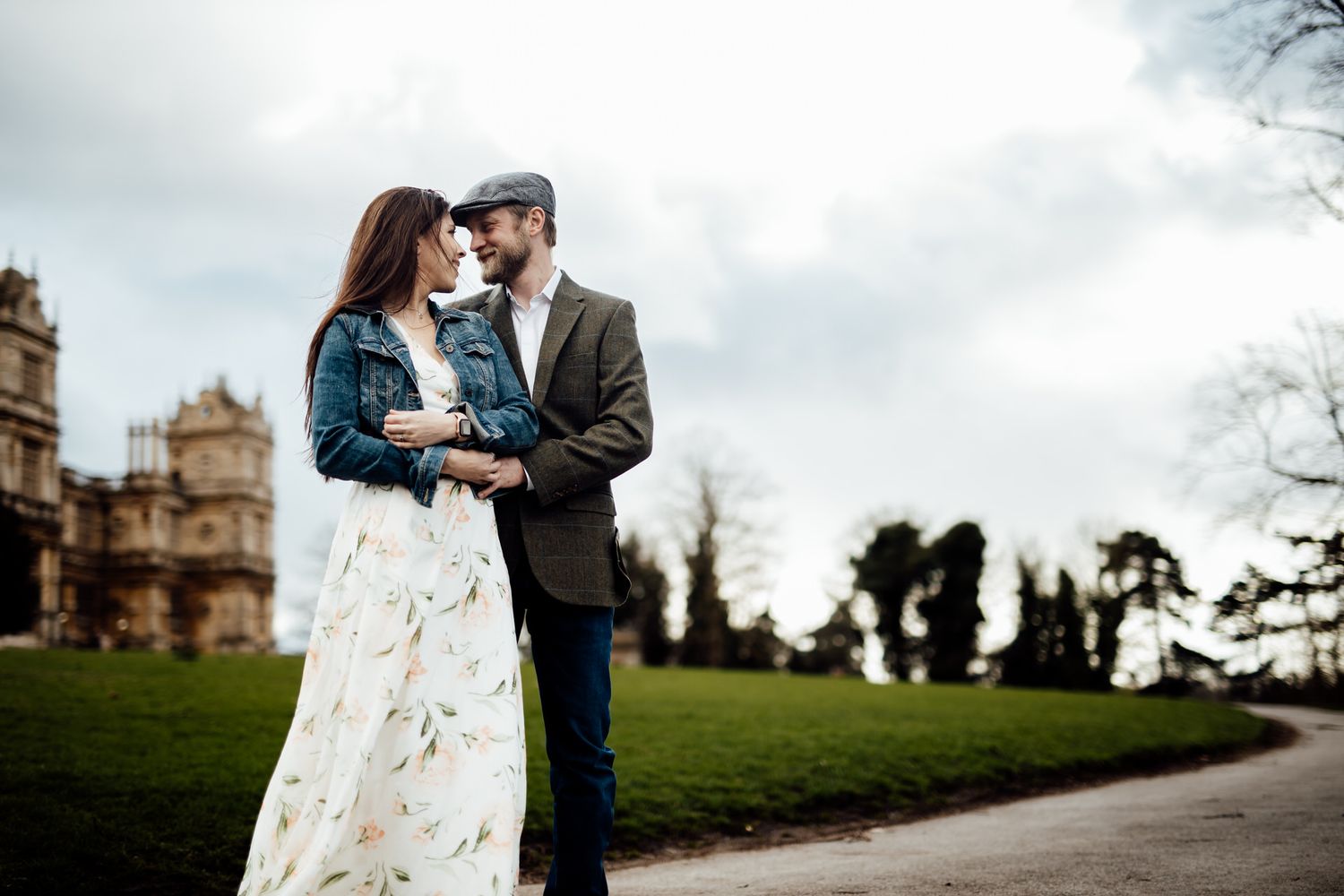 Romantic couple poses against historic building backdrop on cloudy day.