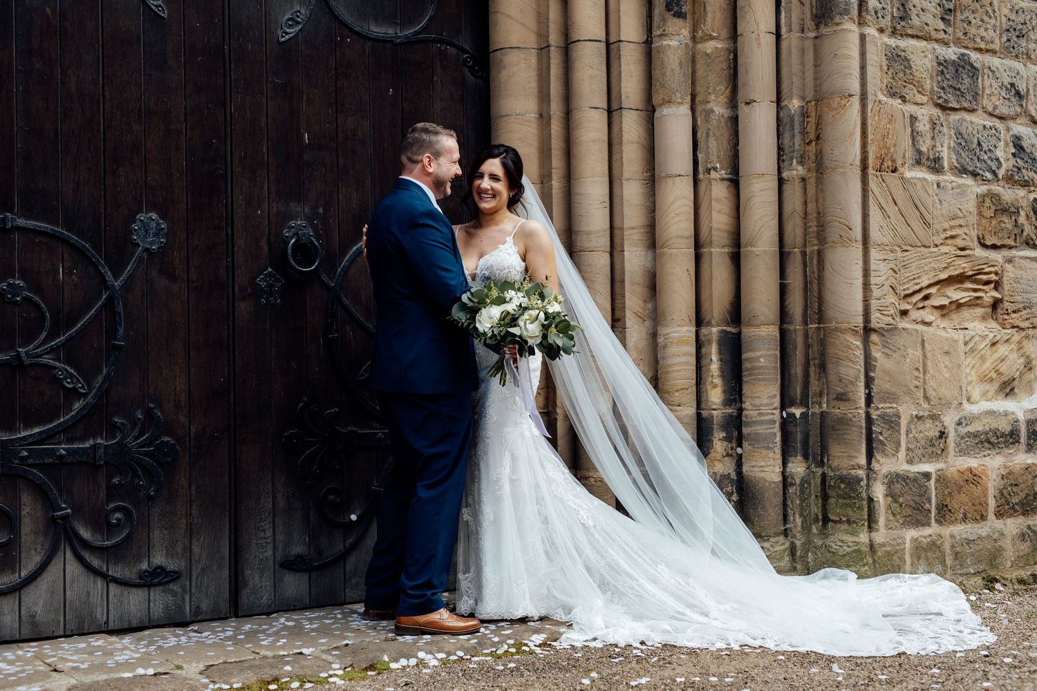 Wedding photography session against gothic stone church architecture and wooden doors.