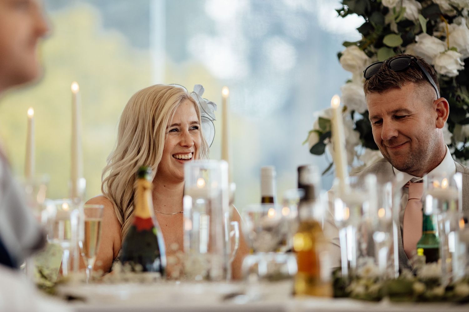 Guests seated at an elegant wedding reception table with candles and floral decorations.