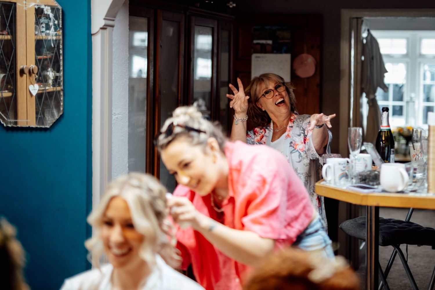 Wedding party members celebrate in a room with bright blue walls.