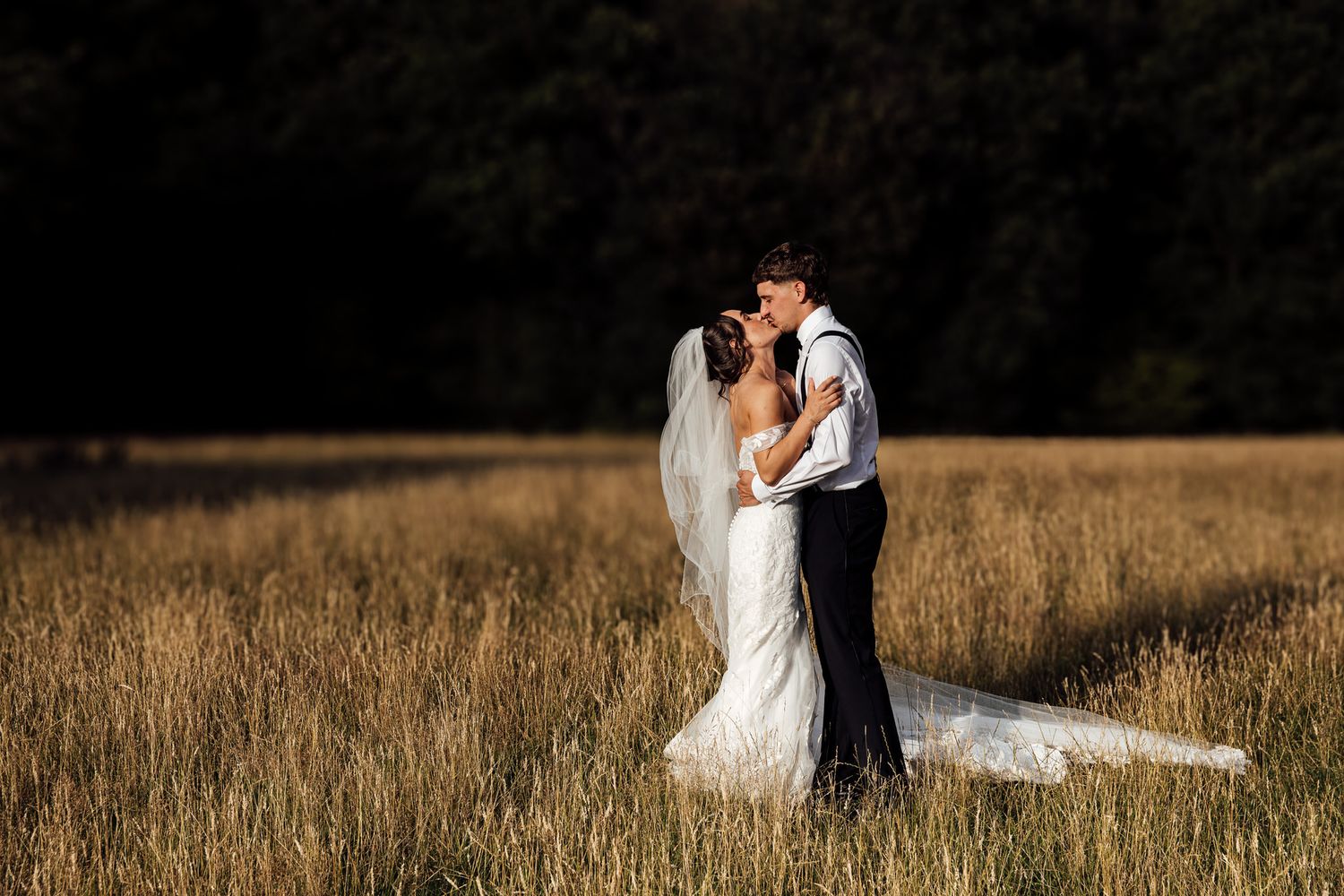 Romantic couple portraits in golden field during sunset wedding photoshoot.