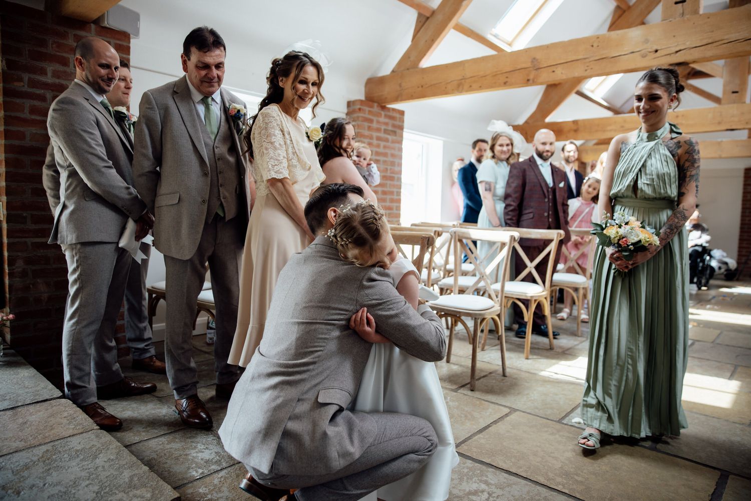 Wedding ceremony in progress inside rustic venue with exposed beams and natural light.