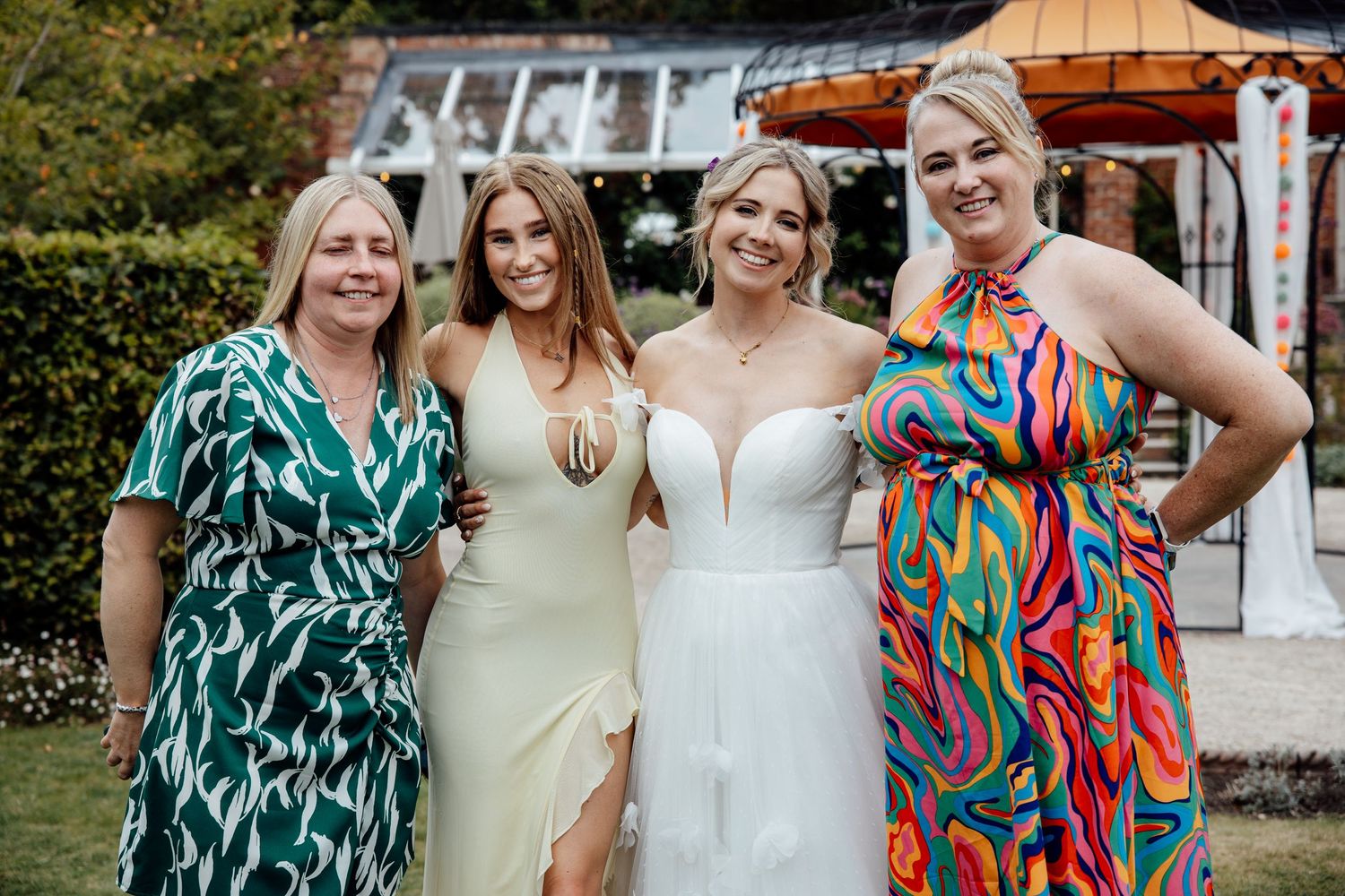Wedding party members in colorful dresses and white gowns gather for group photos.