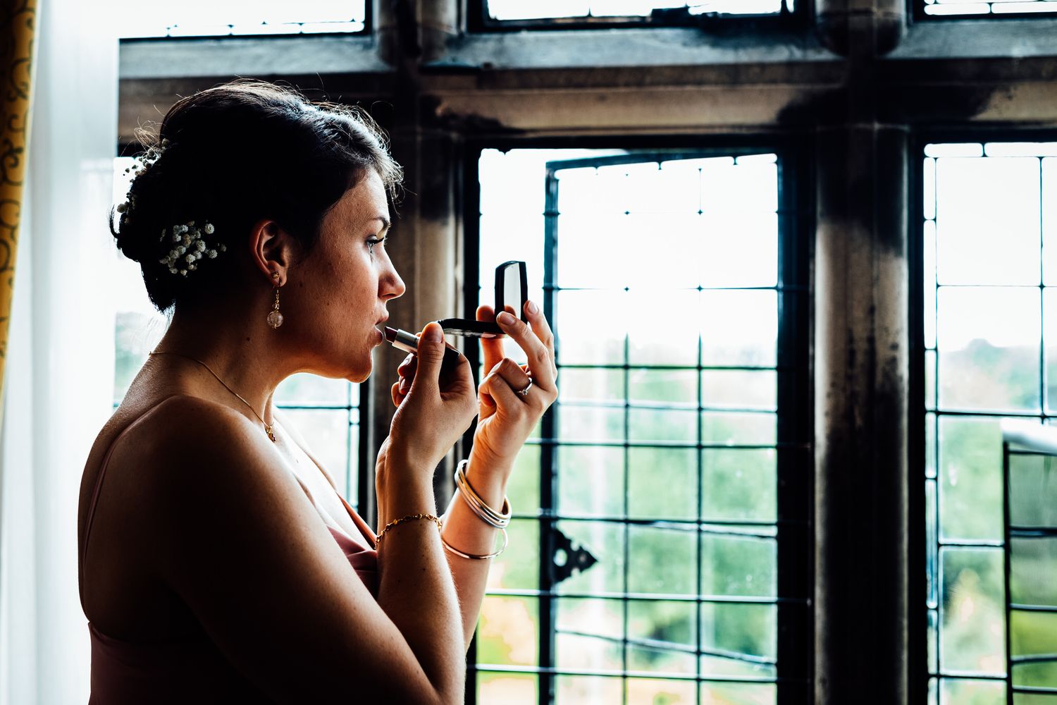 Someone in formal attire looking out large windows in natural light.
