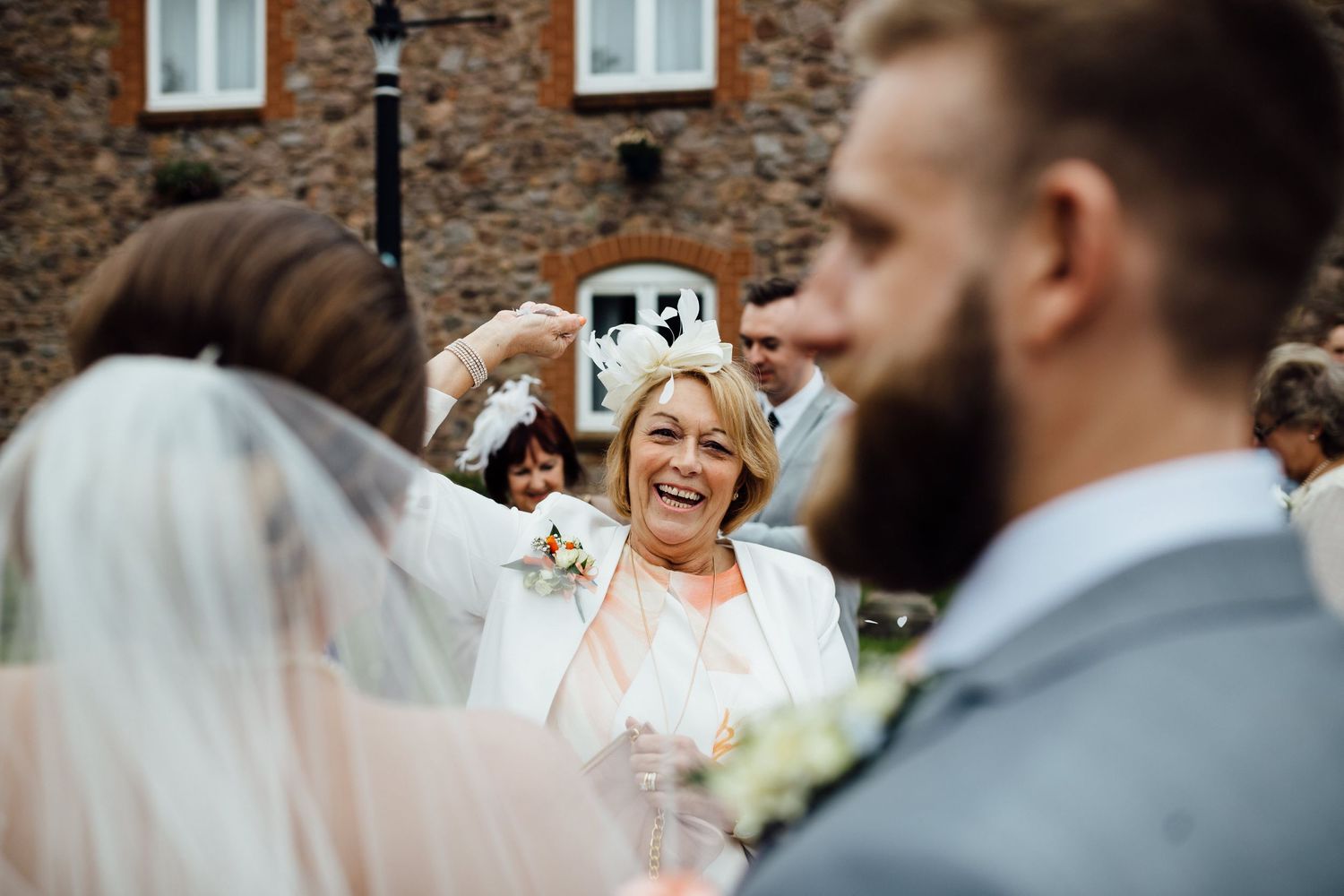Wedding guests gather outside a historic brick building during the celebration.