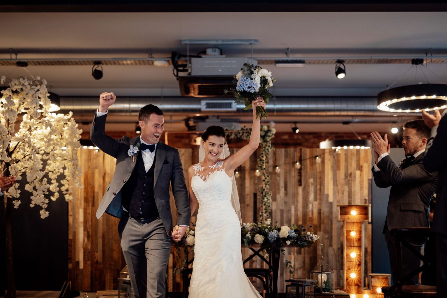 Wedding celebration in modern venue with wooden accent walls and decorative lighting.
