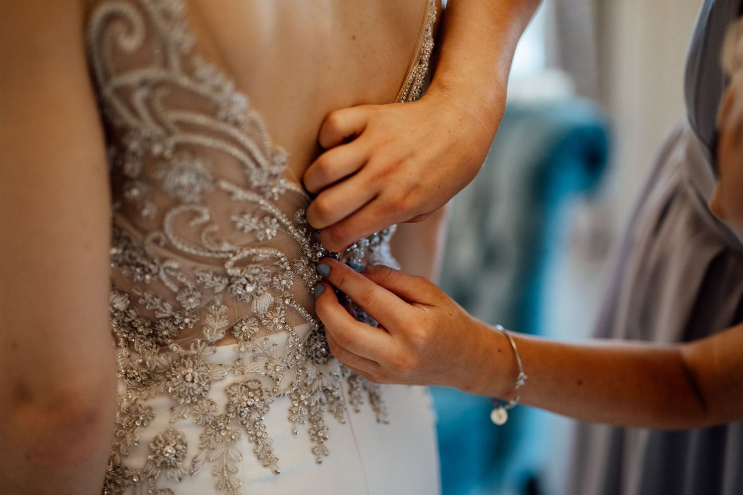Close-up detail of intricate beading and embellishments being adjusted on a wedding dress.