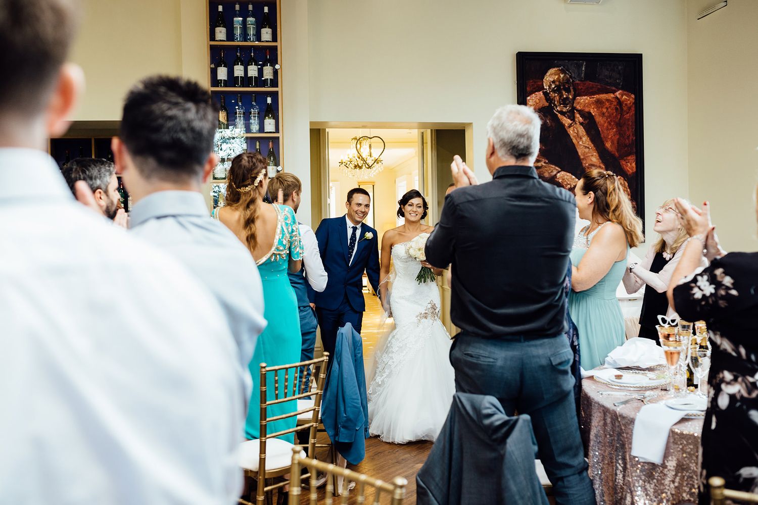 Wedding reception guests mingle and celebrate in an elegant indoor venue with ambient lighting.