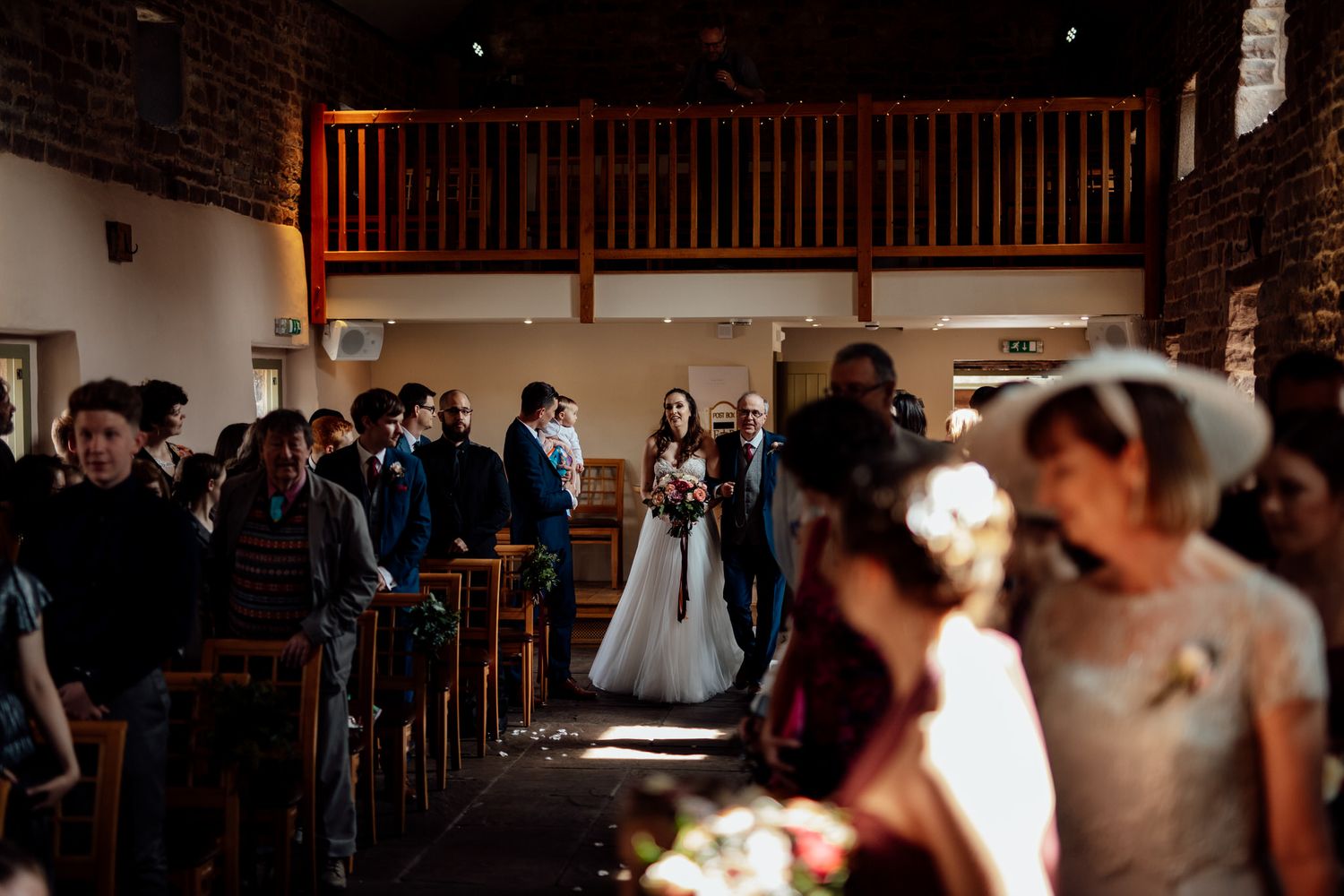 Wedding guests gather in a rustic brick-walled venue for the ceremony.