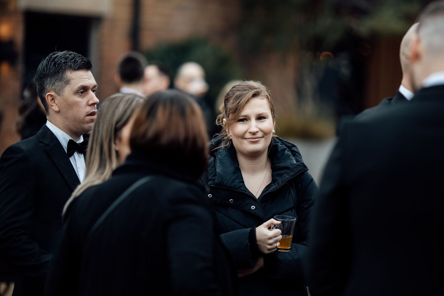 Wedding guests mingle during an outdoor evening reception with ambient lighting.